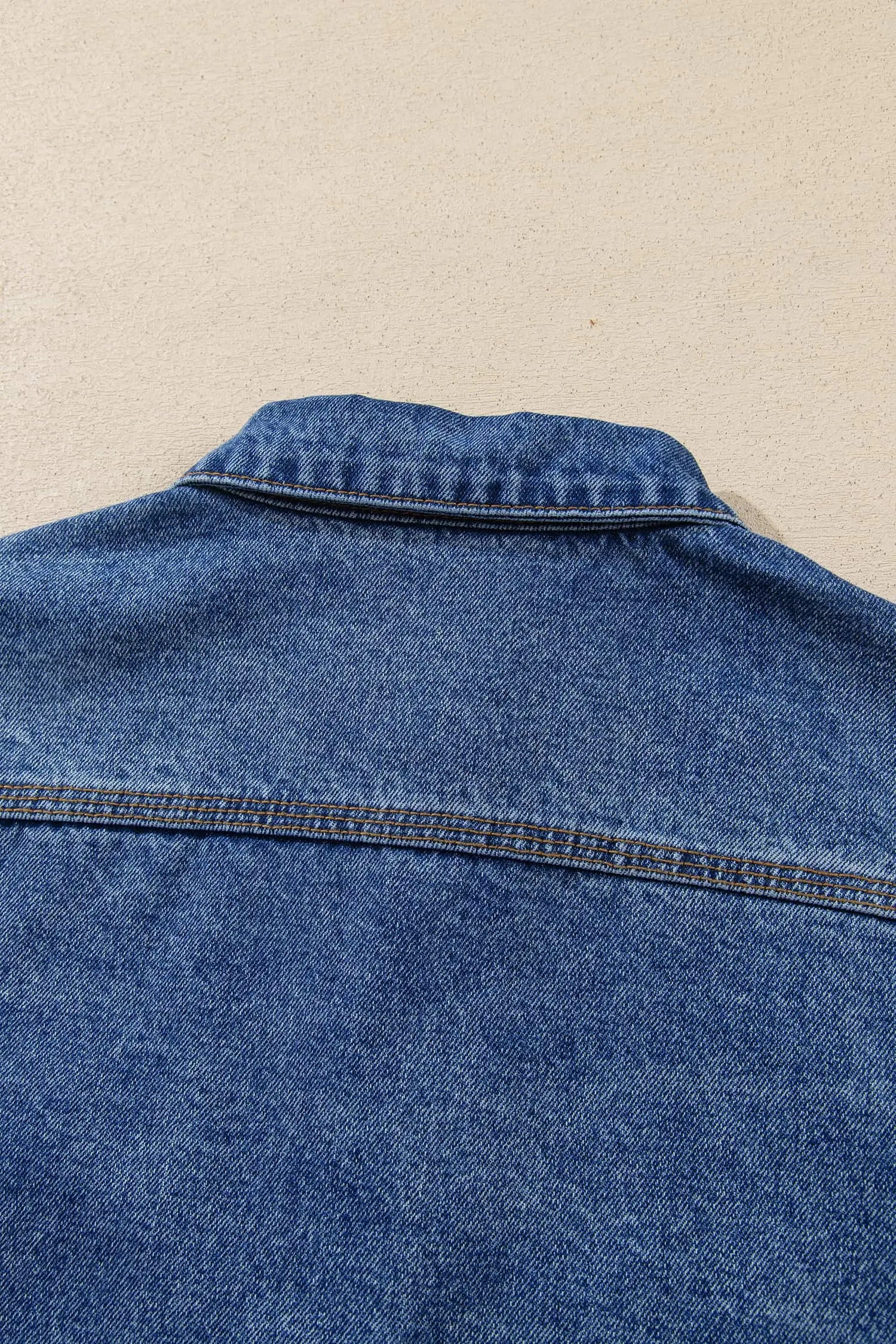 Close-up of blue denim shirt jacket back collar and upper back 