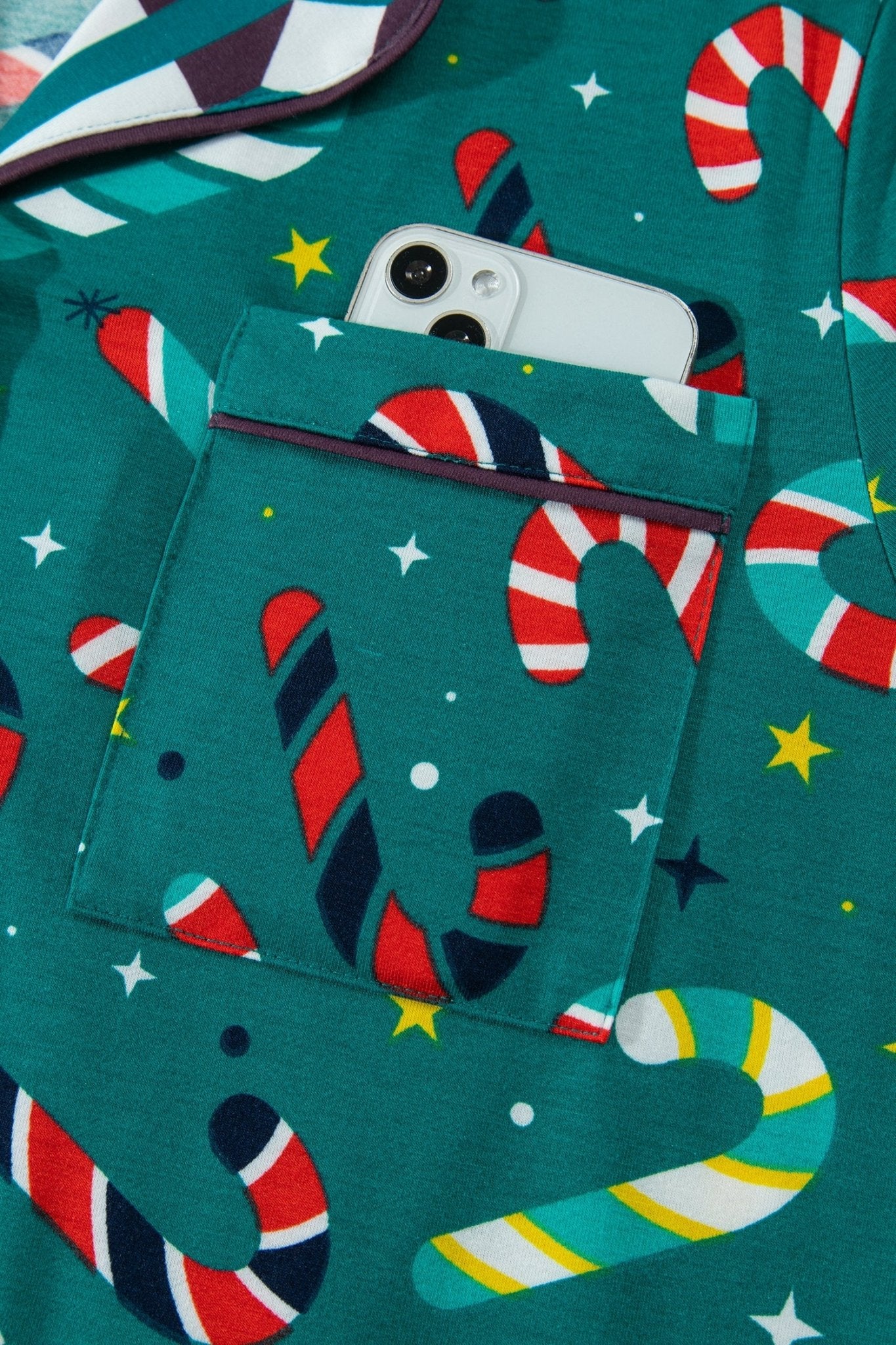 Close-up of green holiday pocket garment with candy cane print and smartphone.