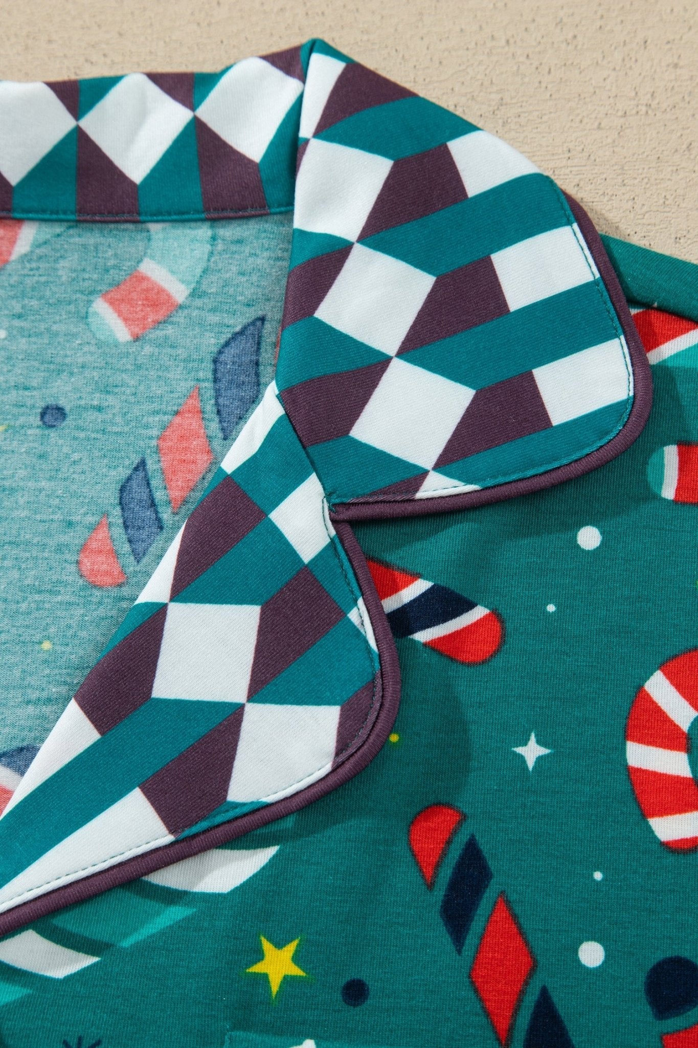 Close-up of teal holiday pajama top with candy cane print and geometric collar.