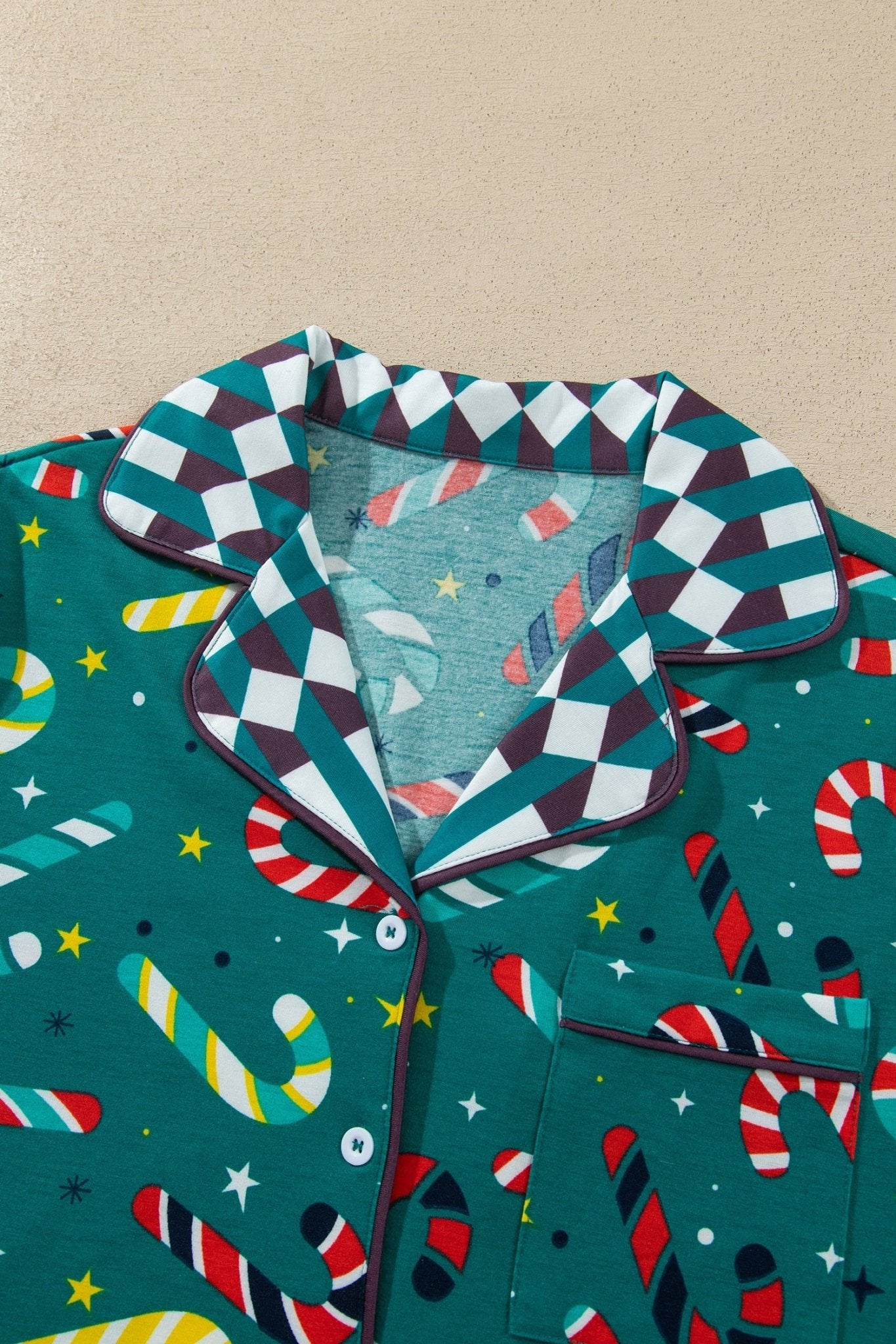Close-up of green pajama top with candy cane-star print and checkered collar.