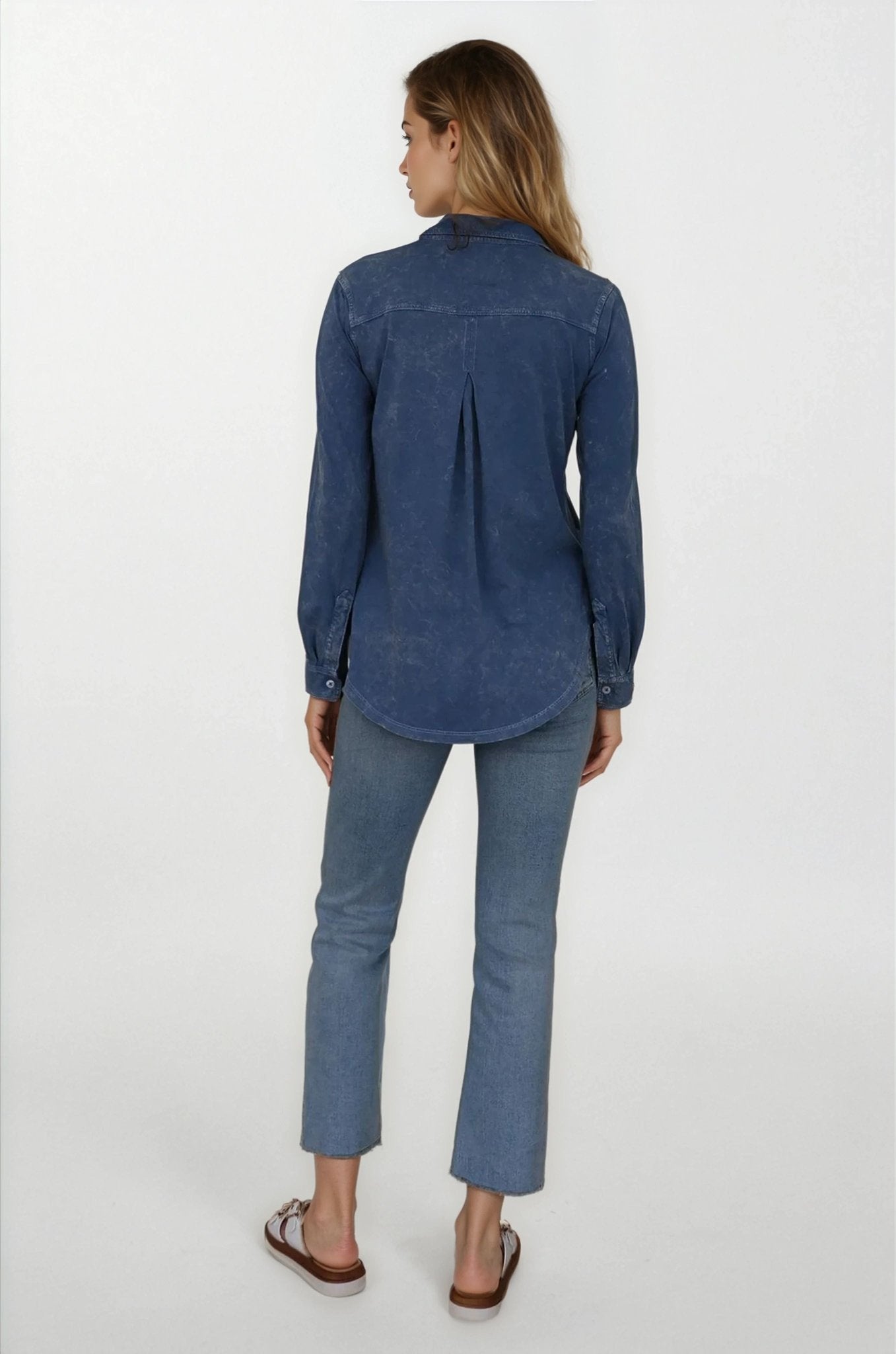 Woman wearing a blue denim shirt and jeans on a white background