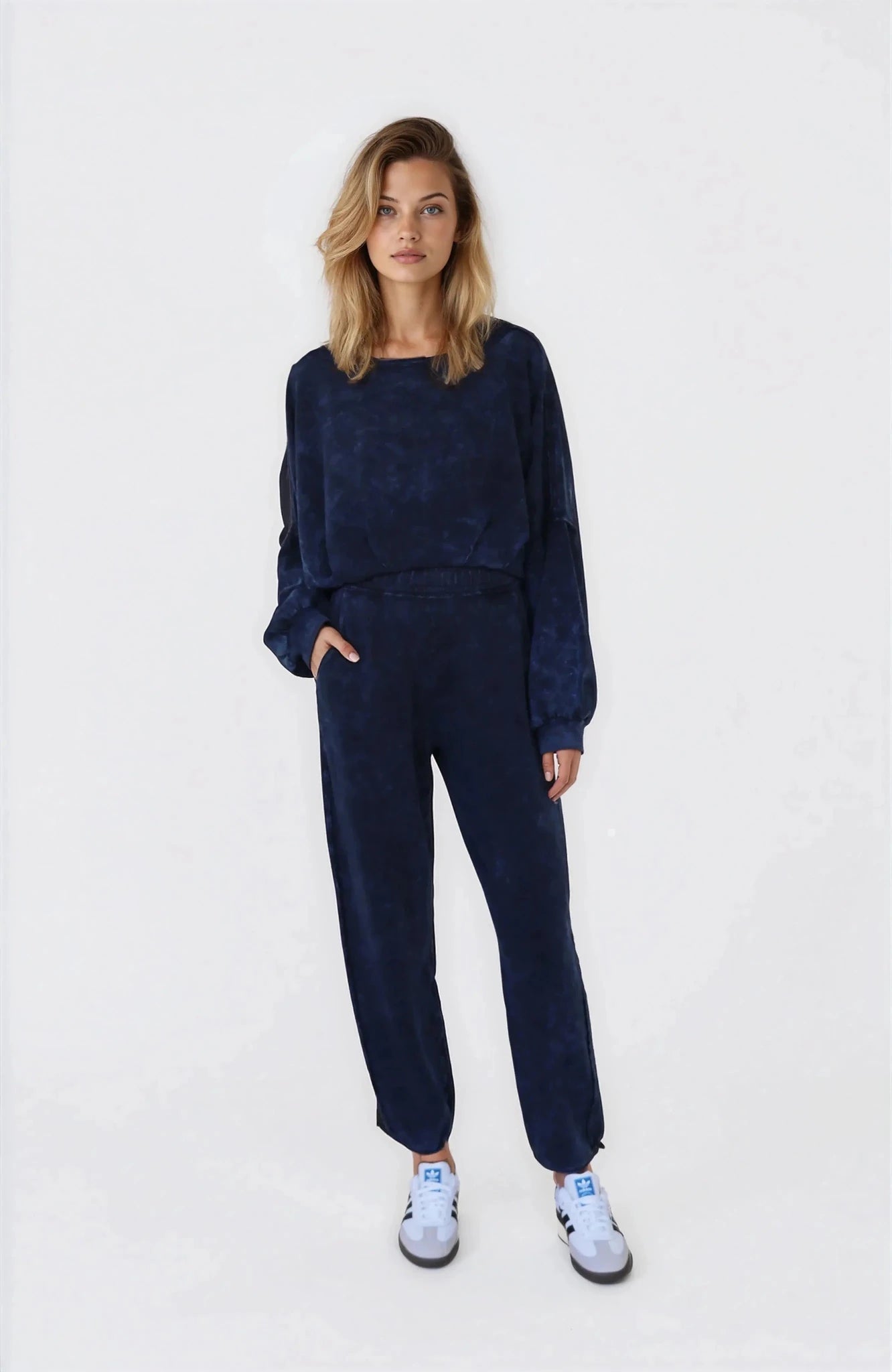 Woman wearing a navy blue outfit with white sneakers on a white background