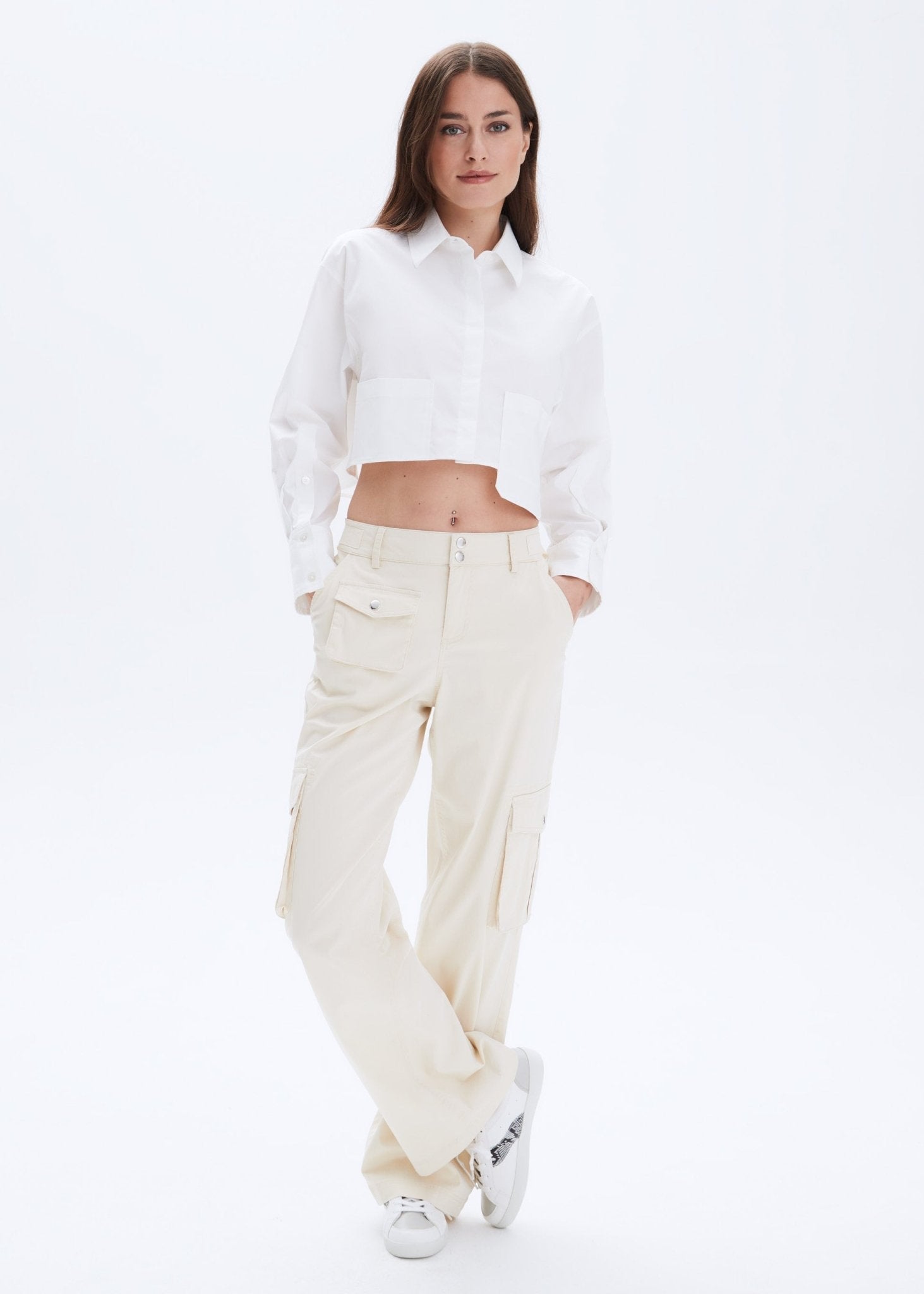 Woman wearing a white shirt and cream pants on a white background