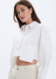 Woman wearing a white cropped shirt with a plain background