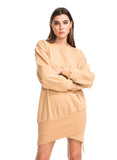 Woman wearing a beige dress with crossed arms on a white background