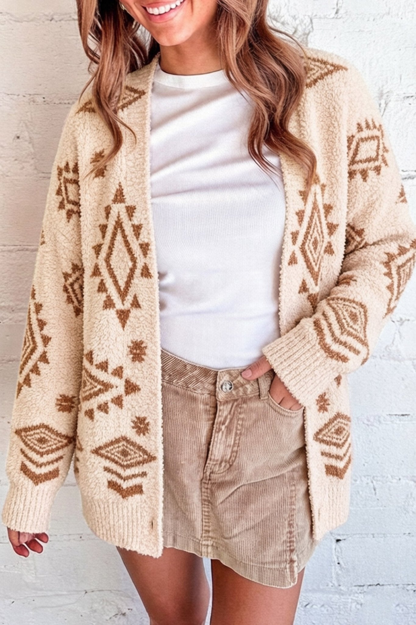 Woman in cream cardigan with brown geometric patterns, white tee, and tan corduroy shorts.