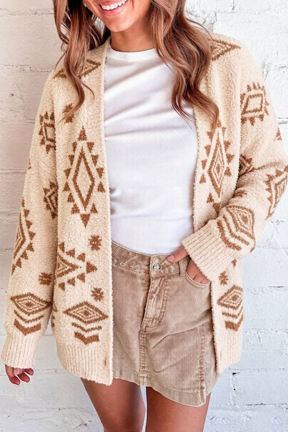 Woman in cream cardigan with brown geometric patterns, white tee, and tan corduroy shorts.