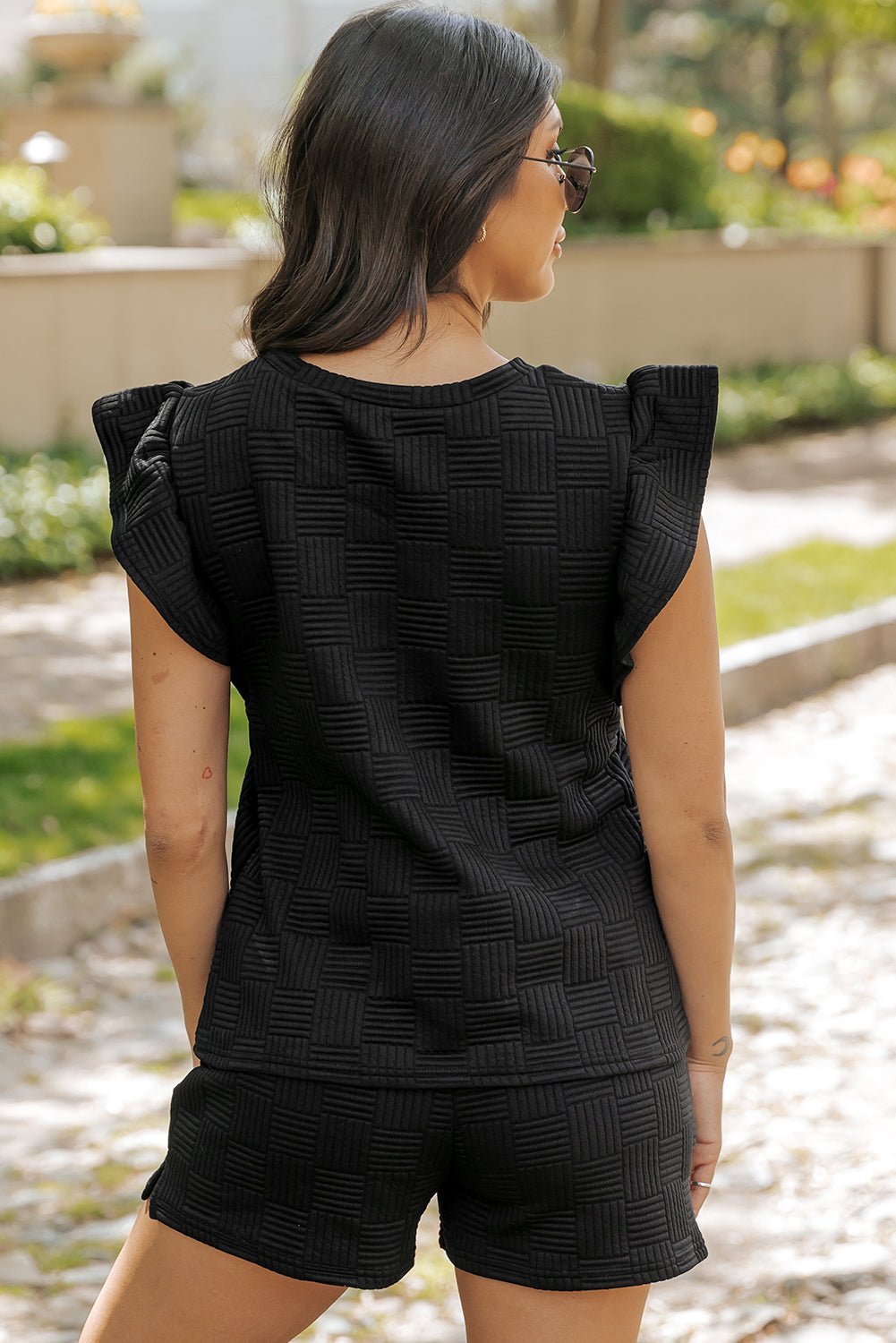 Woman wearing a black textured top and shorts in an outdoor setting