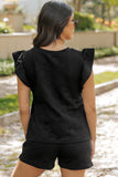 Woman wearing a black textured top and shorts in an outdoor setting