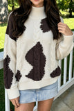 Beige cow print cable knit sweater with pearl bead trim, worn with a light denim mini skirt