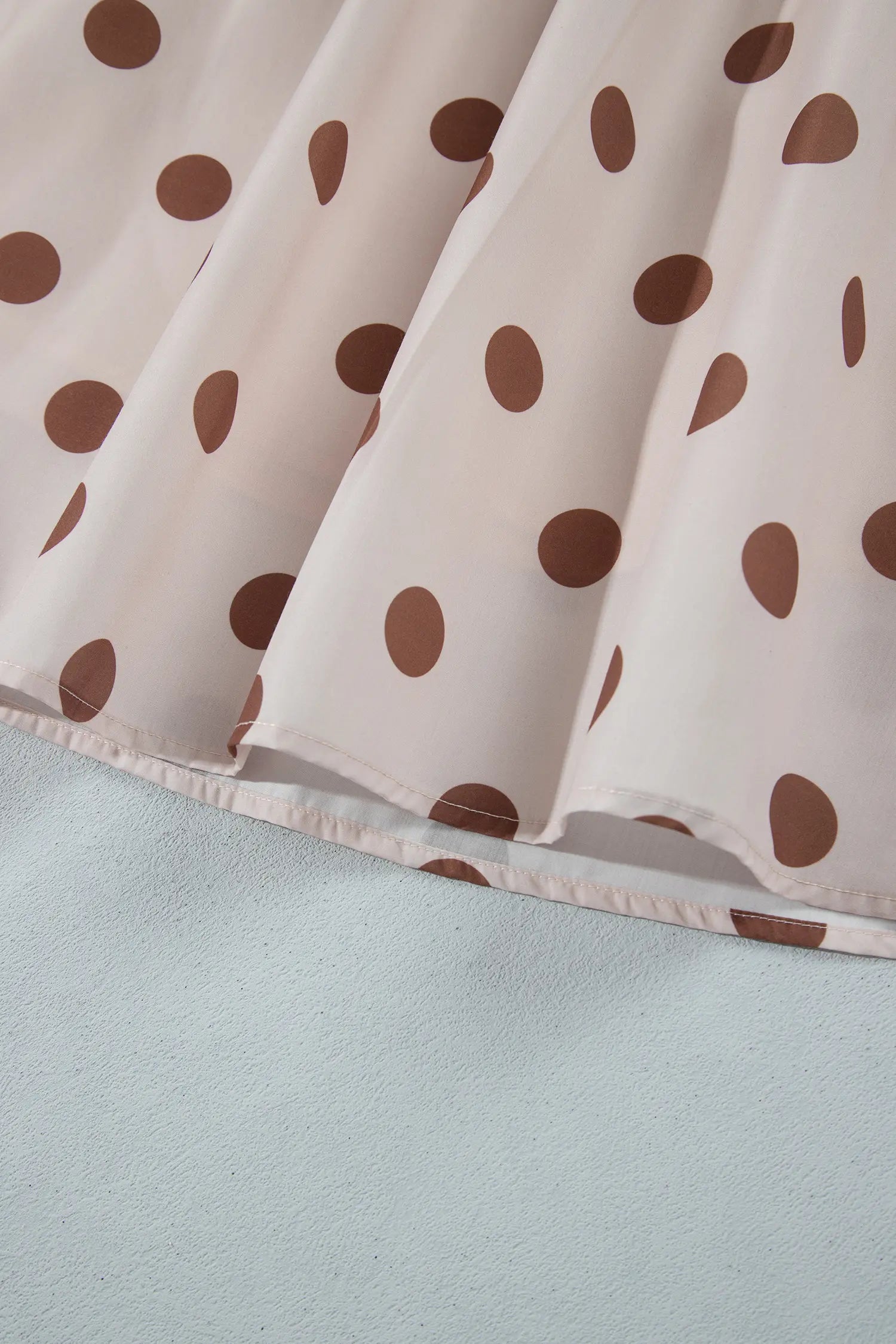 Hem of cream and brown polka dot A-line skirt