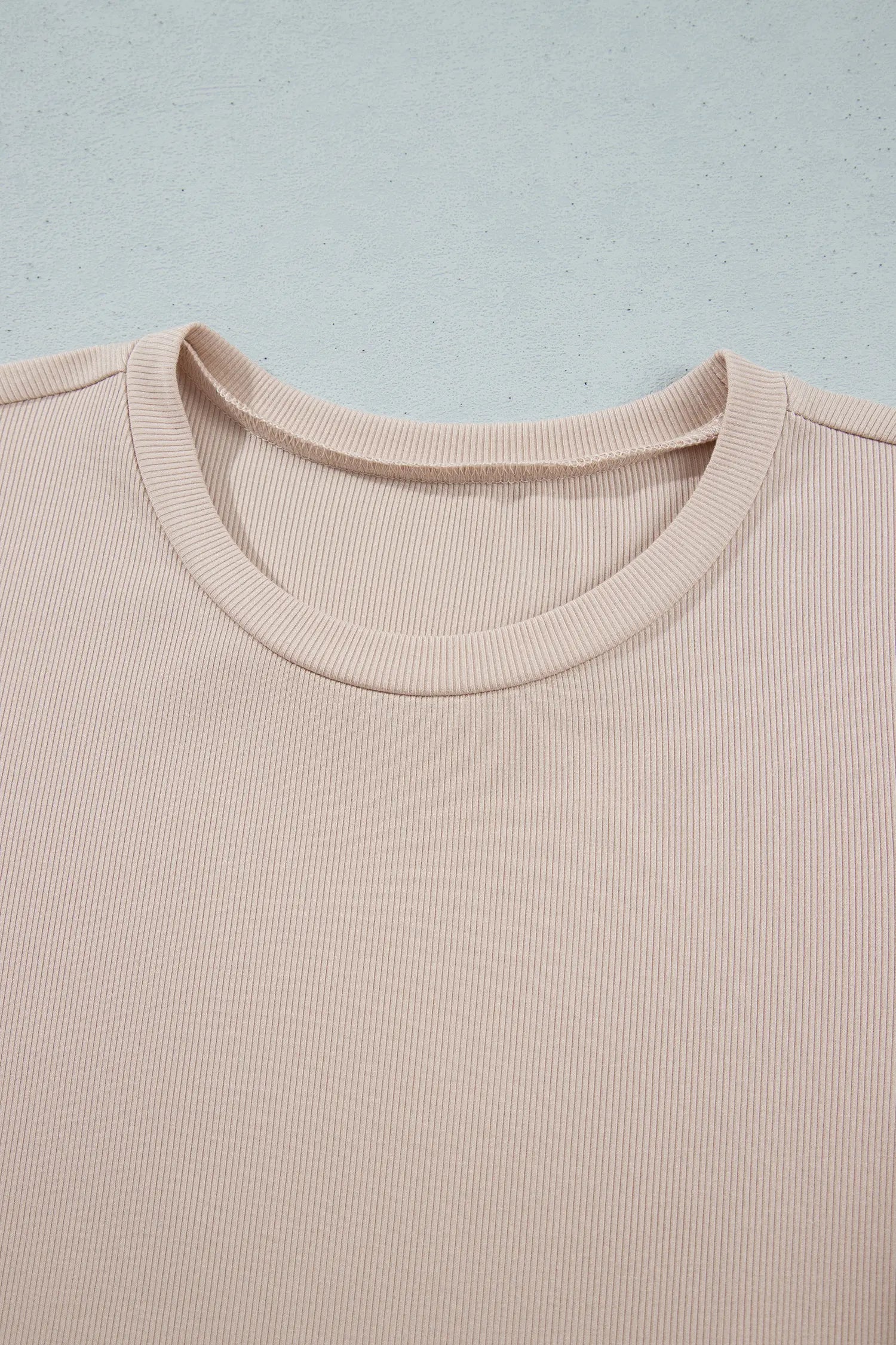 Close-up of ribbed round neckline on beige knit midi dress