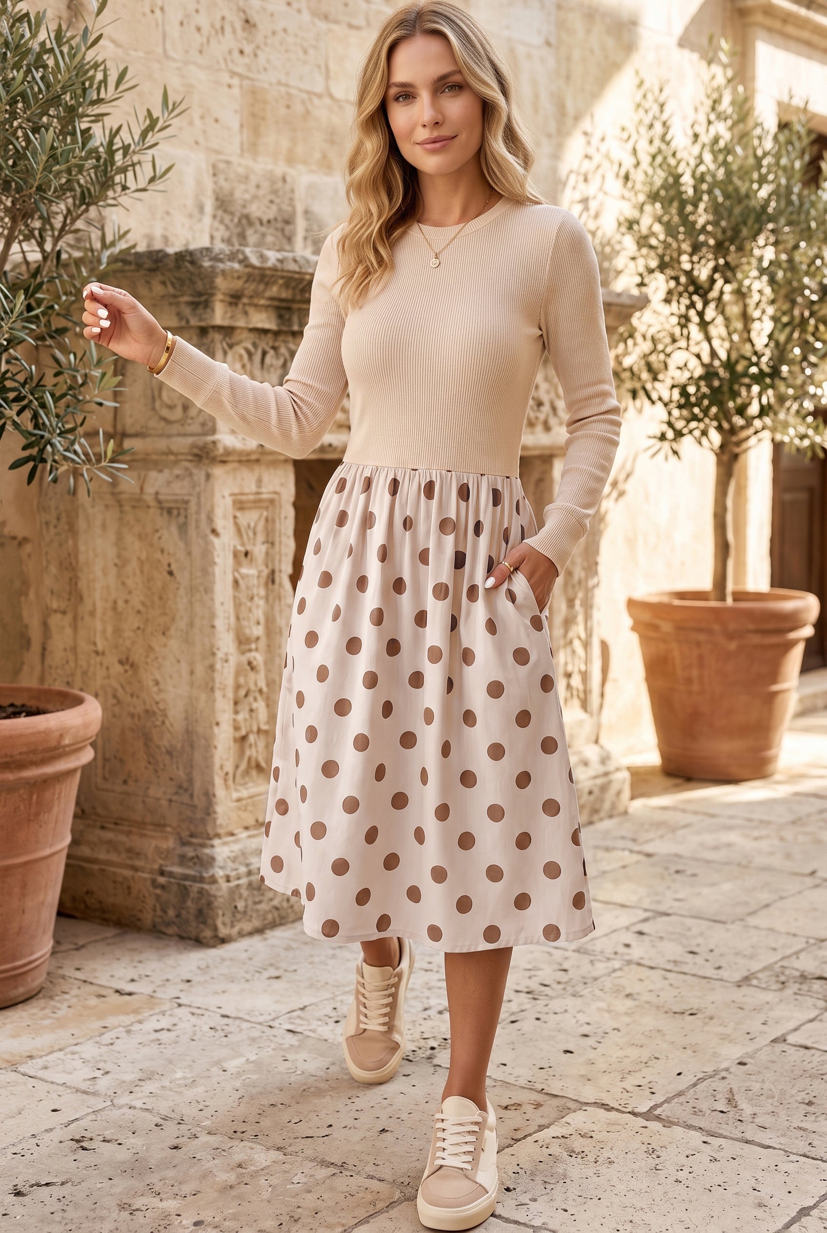 Woman in beige polka dot long sleeve midi dress with hand in pocket, outdoors