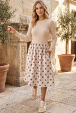 Woman in beige polka dot long sleeve midi dress with hand in pocket, outdoors