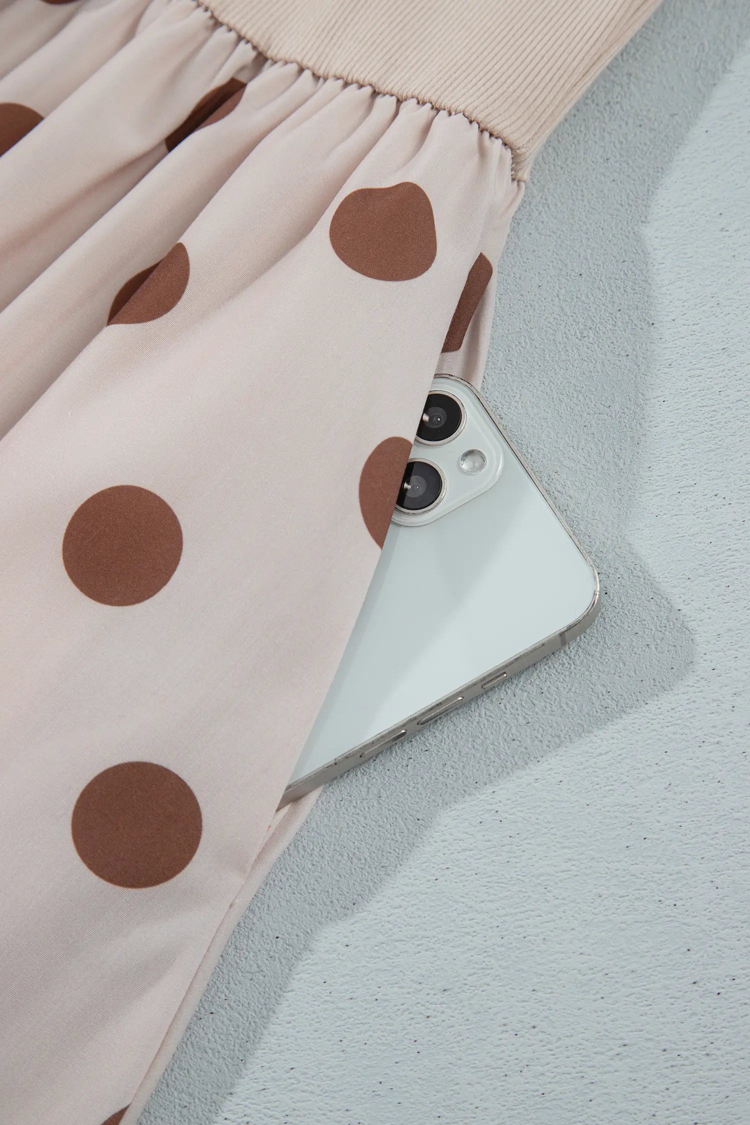 Side pocket holding a phone on beige polka dot midi skirt