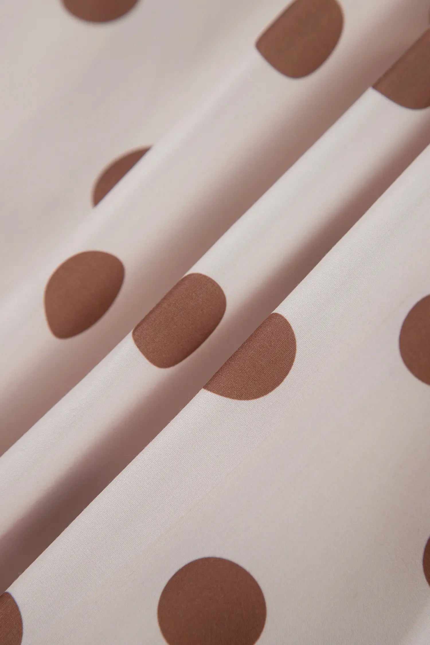 Close-up of cream fabric with large brown polka dots