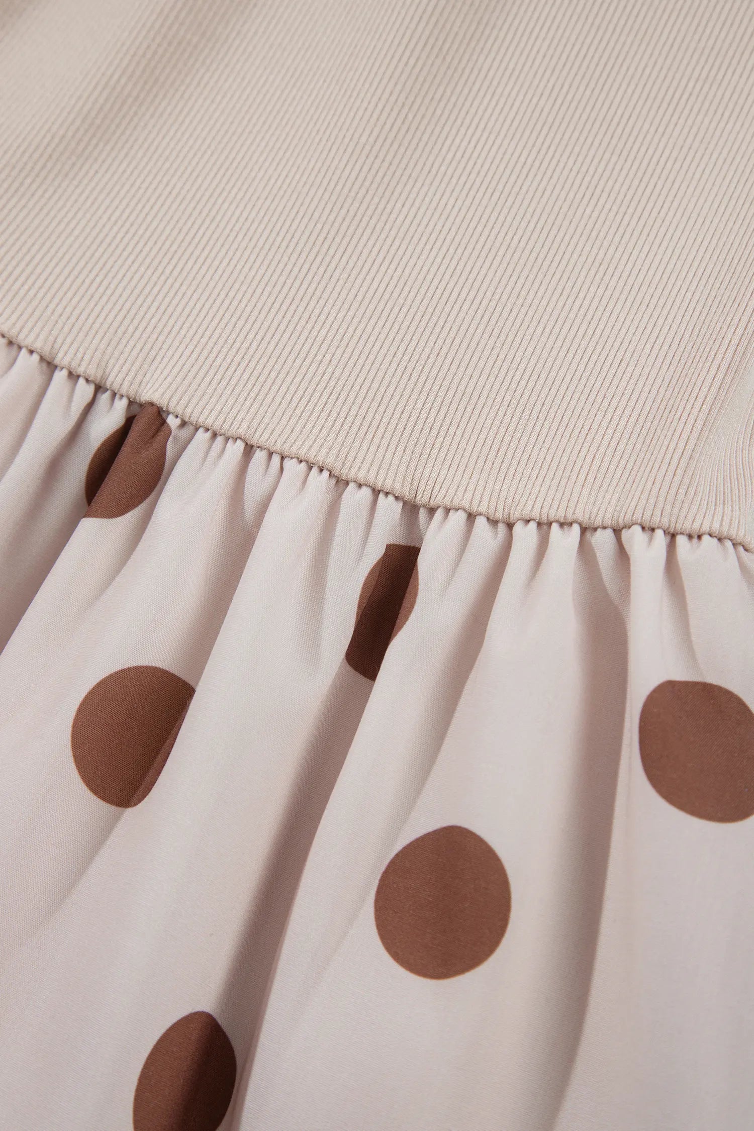 Gathered waist seam joining ribbed bodice and polka dot skirt