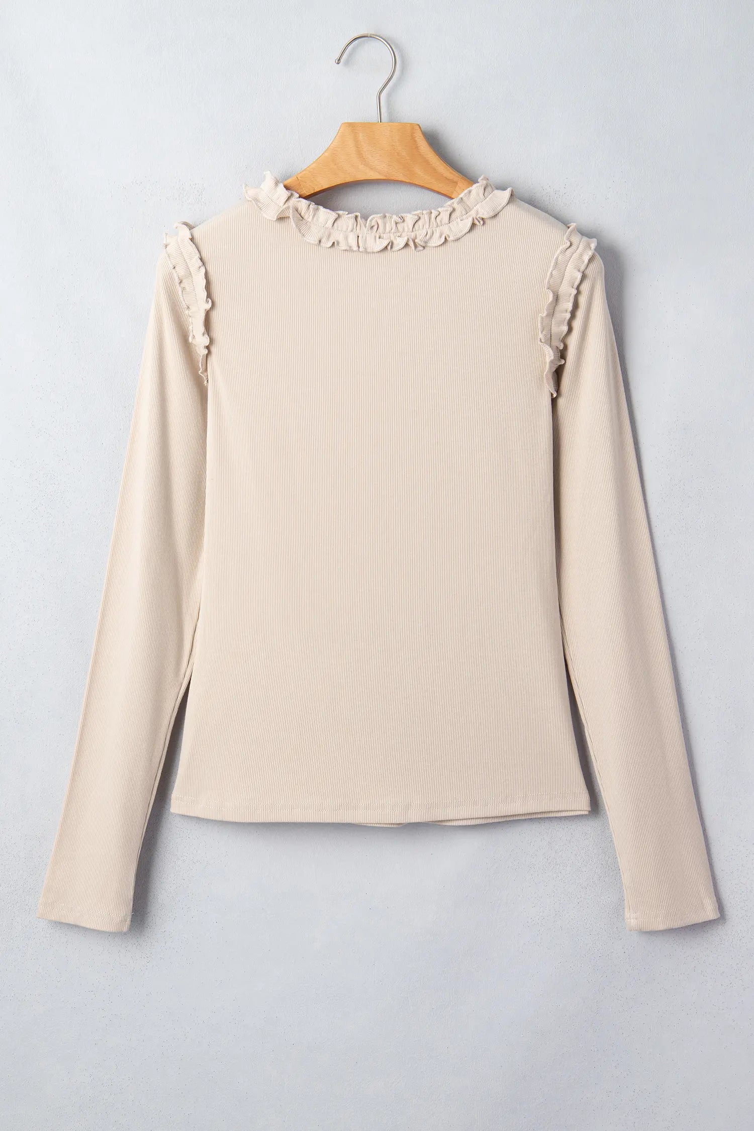 Beige ribbed long sleeve top with frill shoulder trim on a hanger