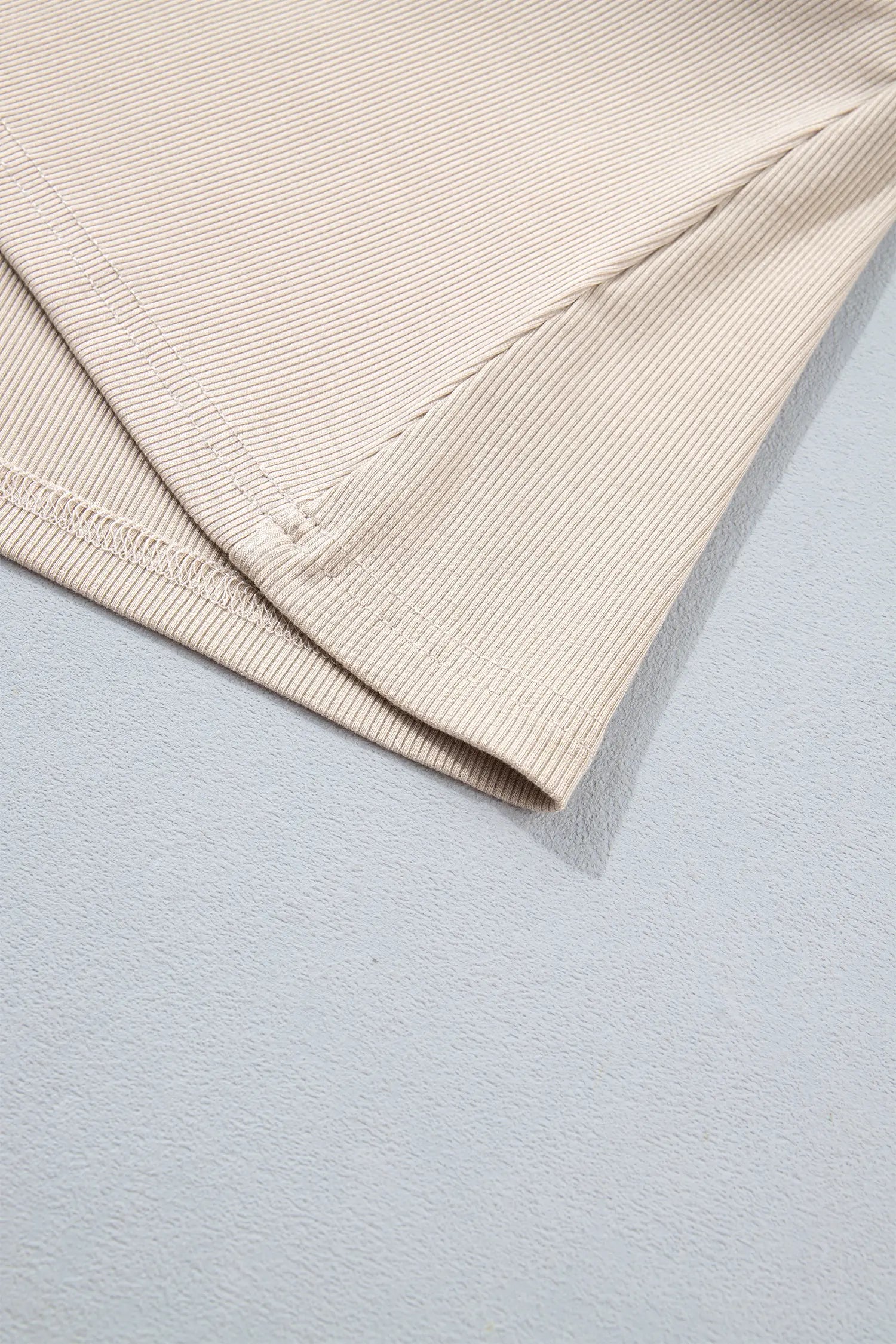 Close-up of hem stitching on beige ribbed knit top