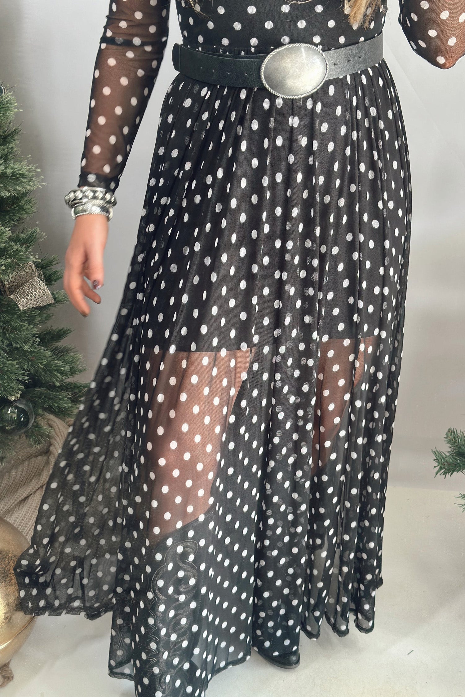 Sheer polka dot mesh maxi dress over black slip, styled with a silver buckle belt