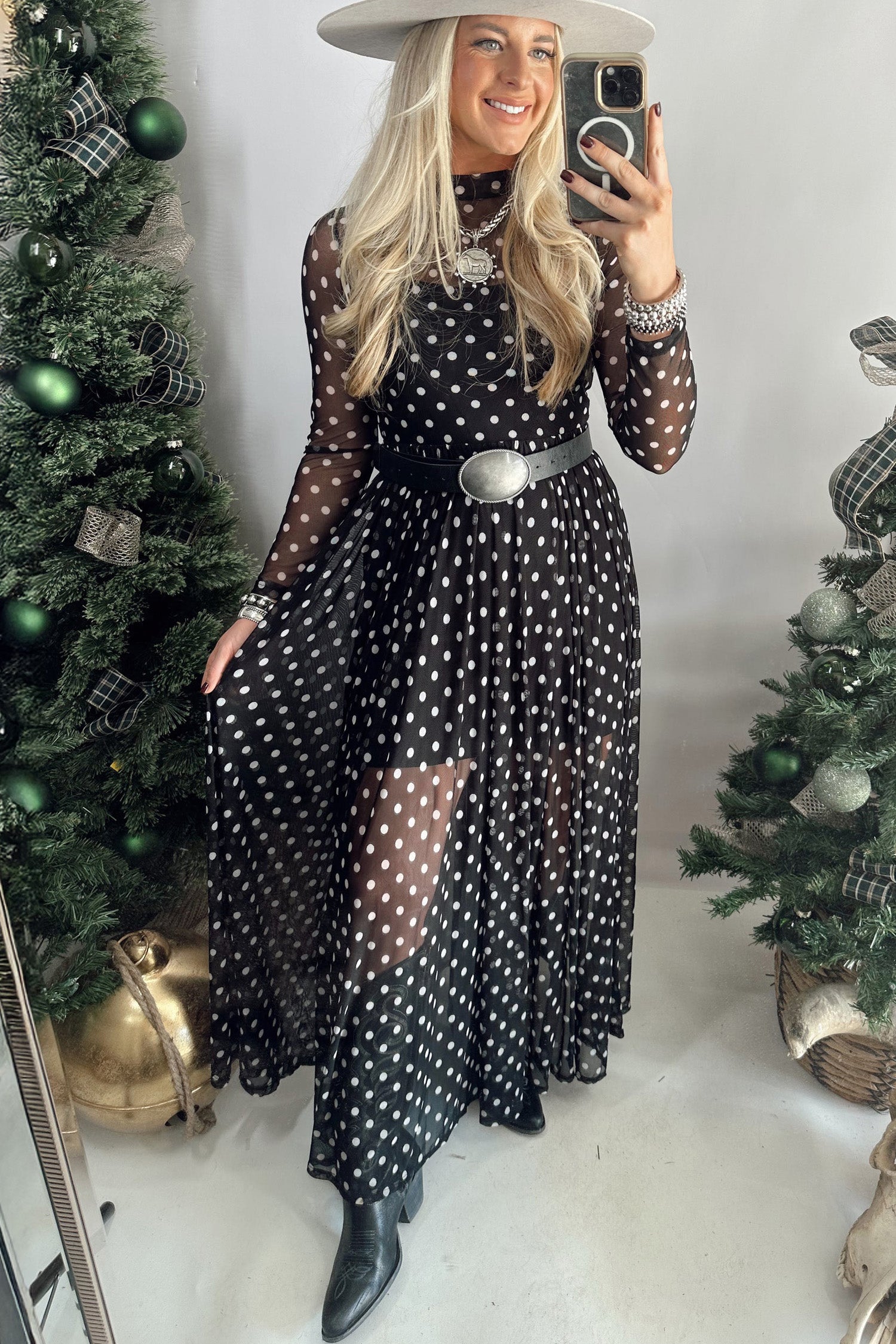 Woman in black polka dot mesh maxi dress with belt, white hat and black boots