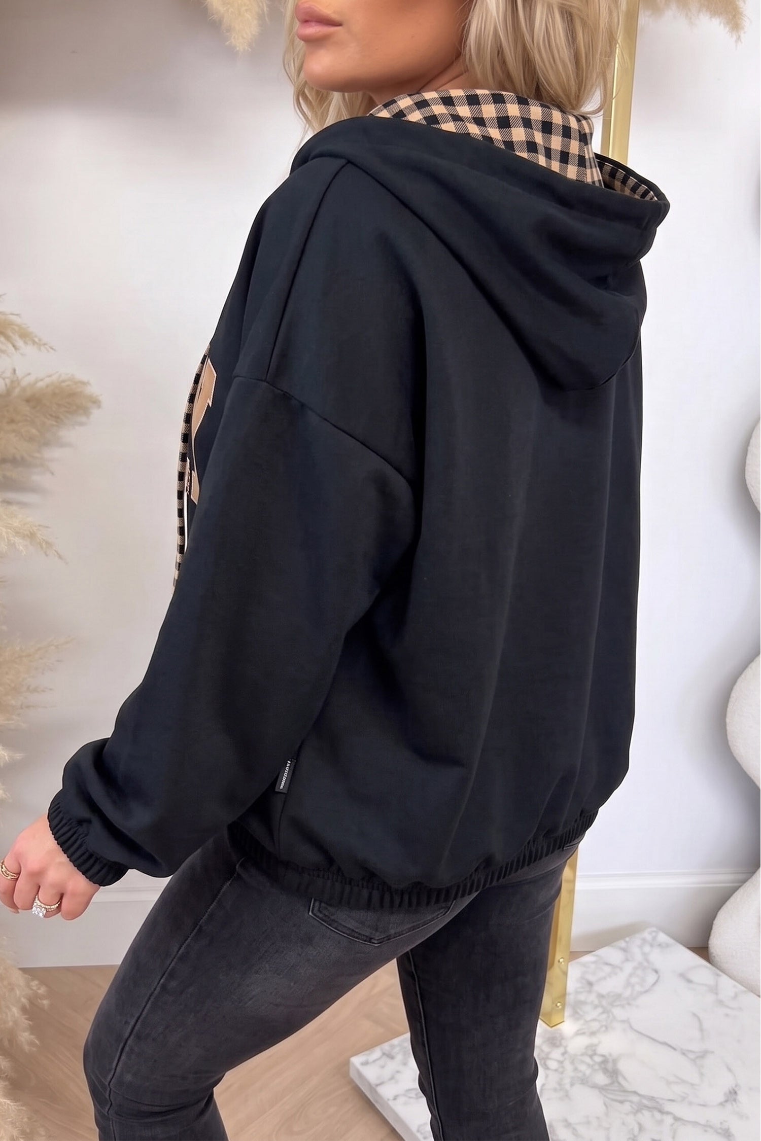 Black PRAY graphic hoodie, back view showing plaid-lined hood