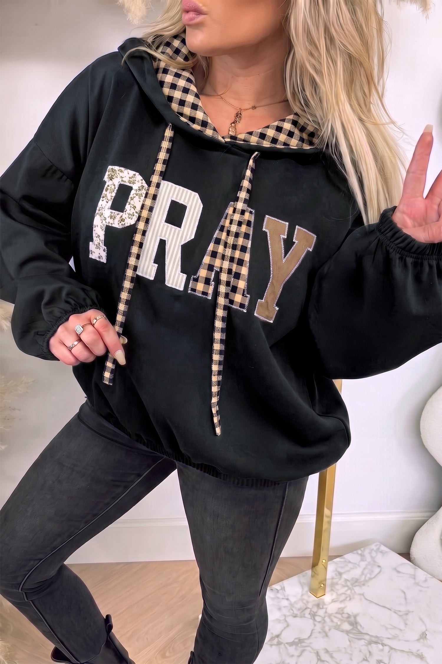 Black PRAY letter graphic hoodie with plaid hood lining and drawstrings, front
