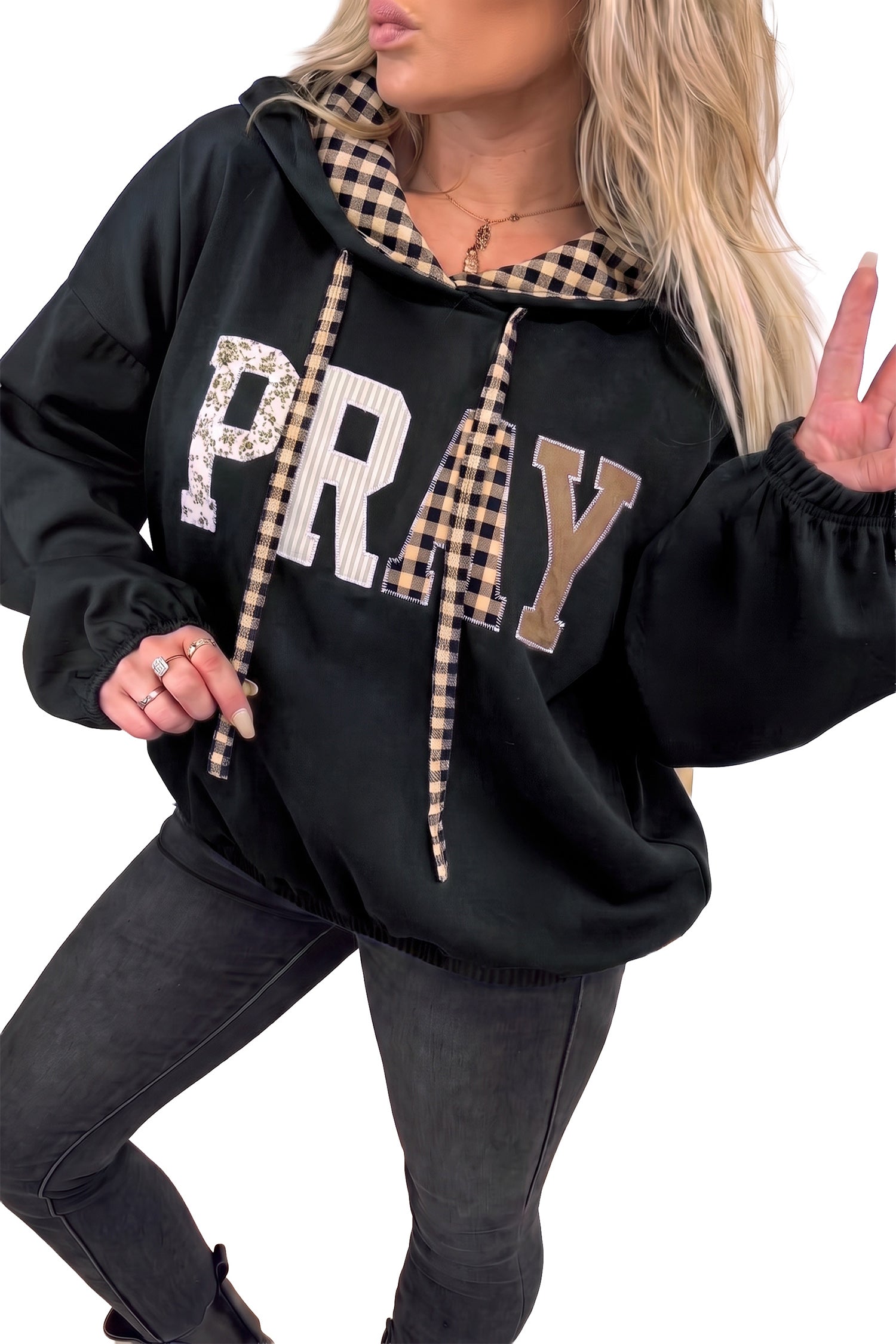 Women's black PRAY hoodie with mixed pattern letters, styled with dark jeans