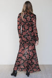 Back view of fitted black floral mesh maxi dress against a white wall
