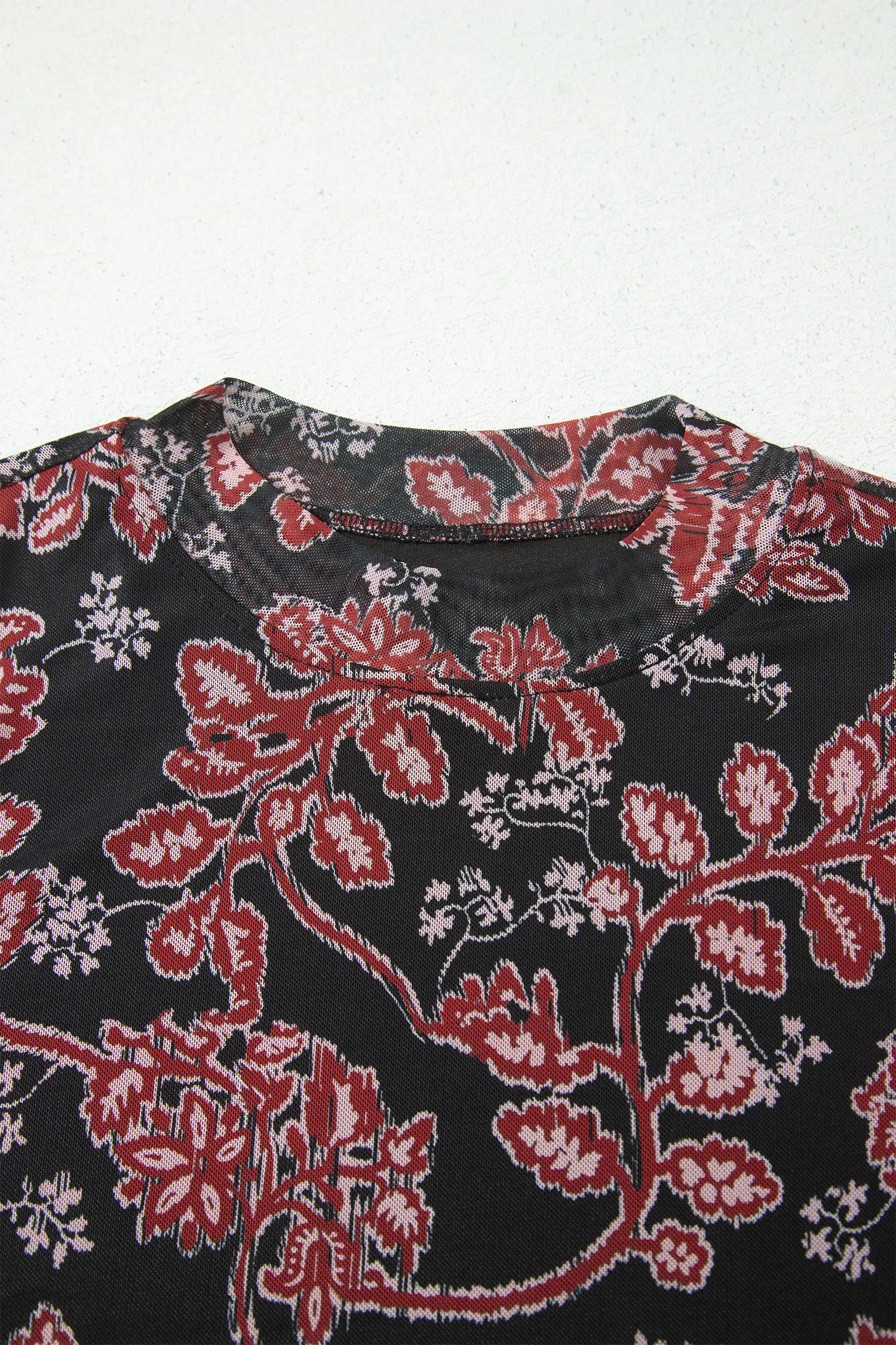 Close-up of red and cream floral print bodice on black mesh dress