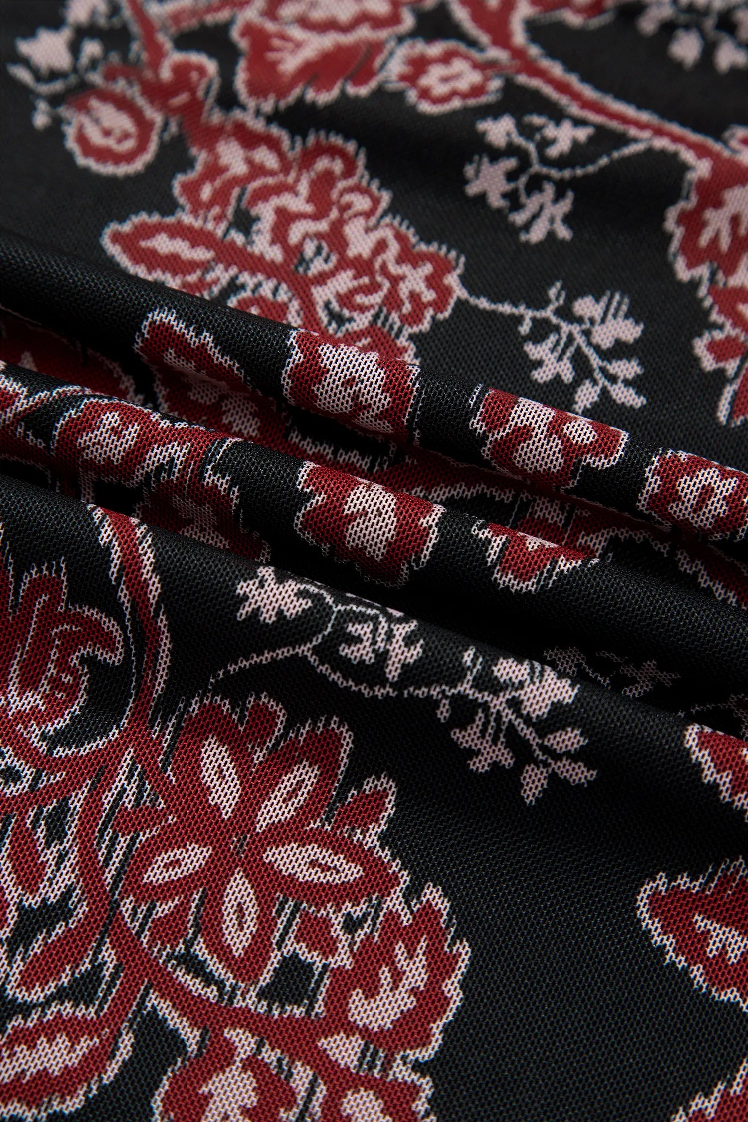 Close-up of black mesh fabric with red, burgundy and cream floral print