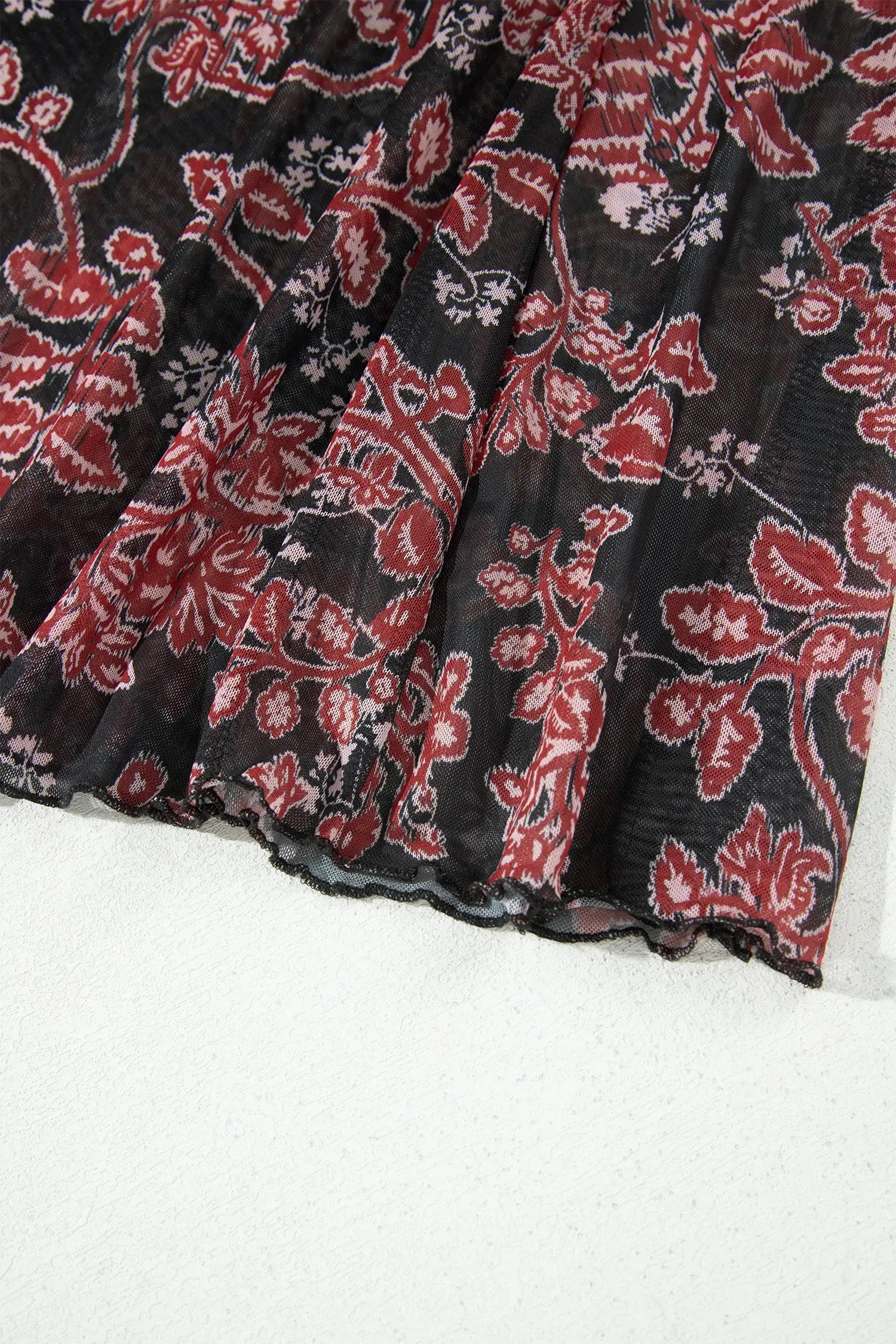 Close-up of flared fluted hem on black floral mesh maxi dress