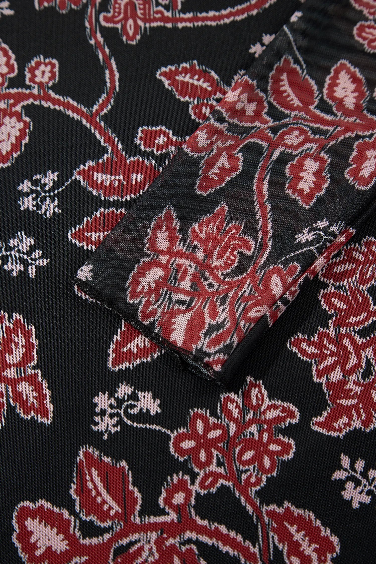Close-up of long mesh sleeve with red and cream floral vine print