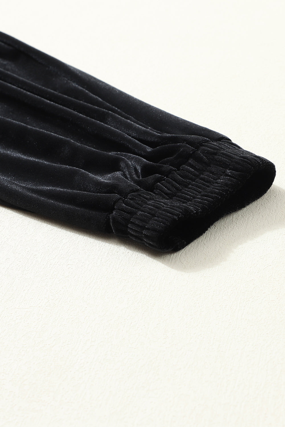 Close-up of gathered elastic ankle cuff on black velvet jogger pants