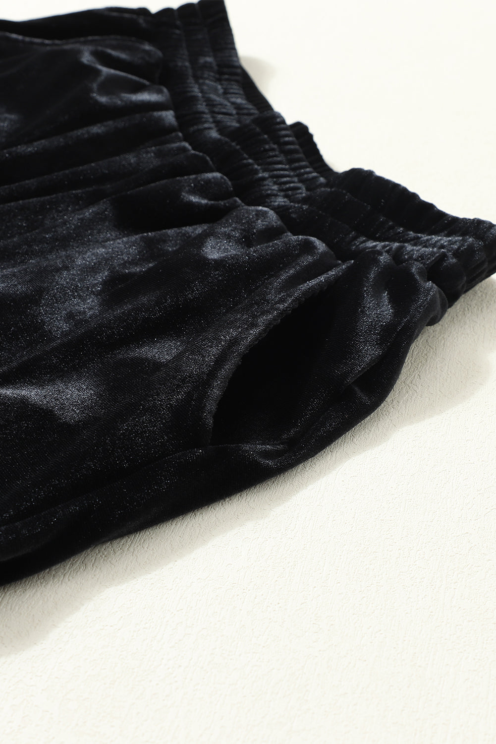 Close-up of elastic waistband and side pocket on black velvet jogger pants
