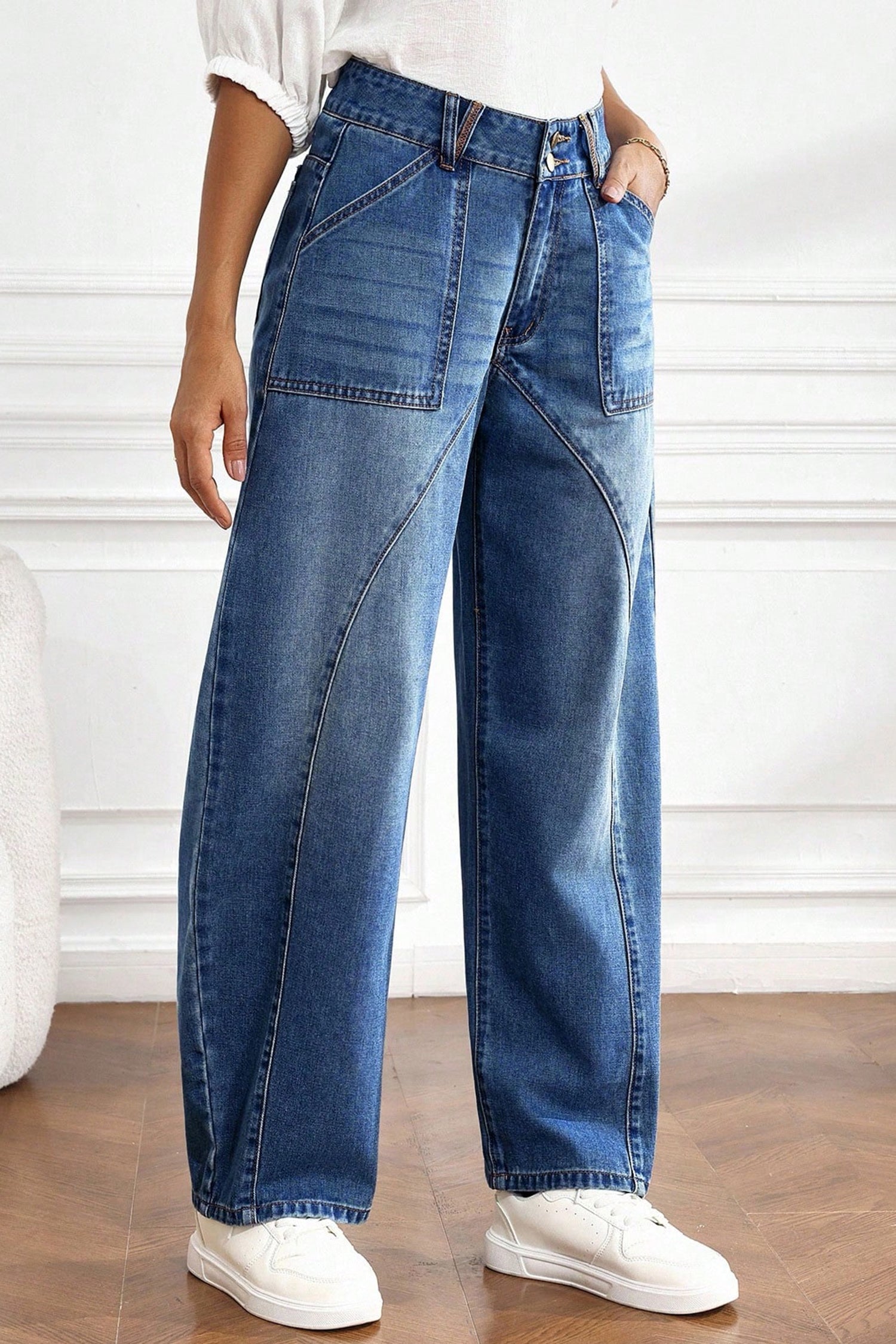 Angled view of medium wash curved seam barrel jeans with front patch pockets