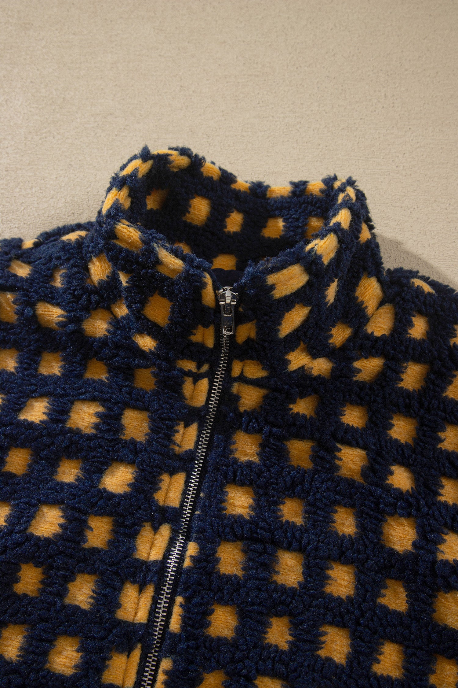 Close-up of stand collar and front zipper on navy check sherpa jacket