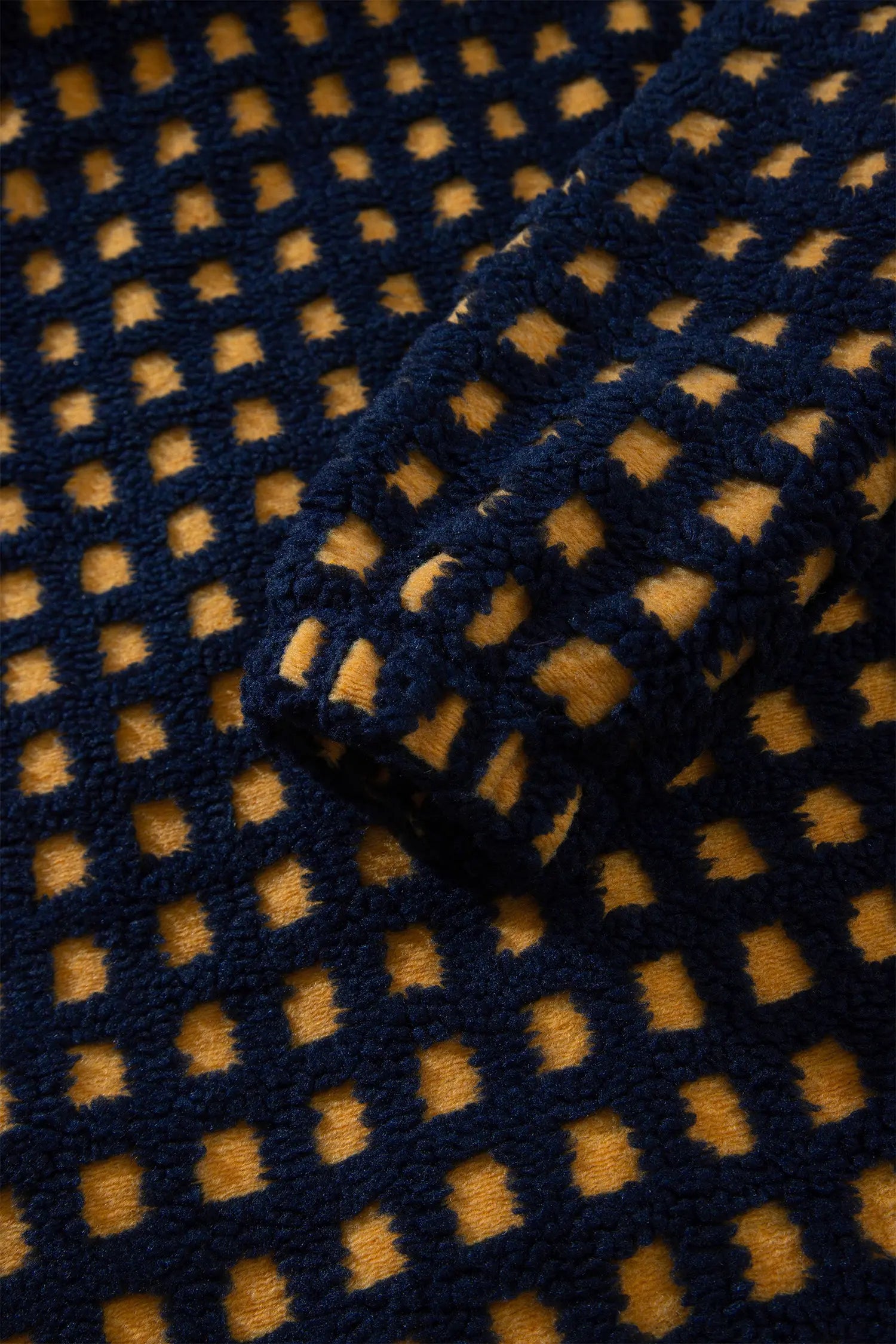 Close-up of plush navy and mustard check sherpa fleece texture