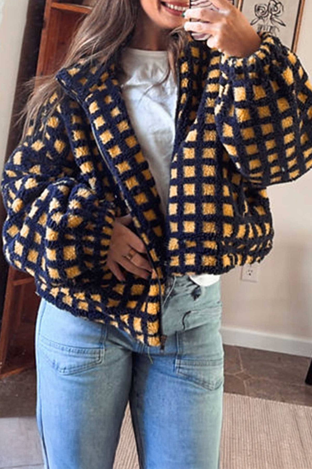 Woman in navy and mustard check sherpa fleece zip up jacket with jeans, mirror selfie