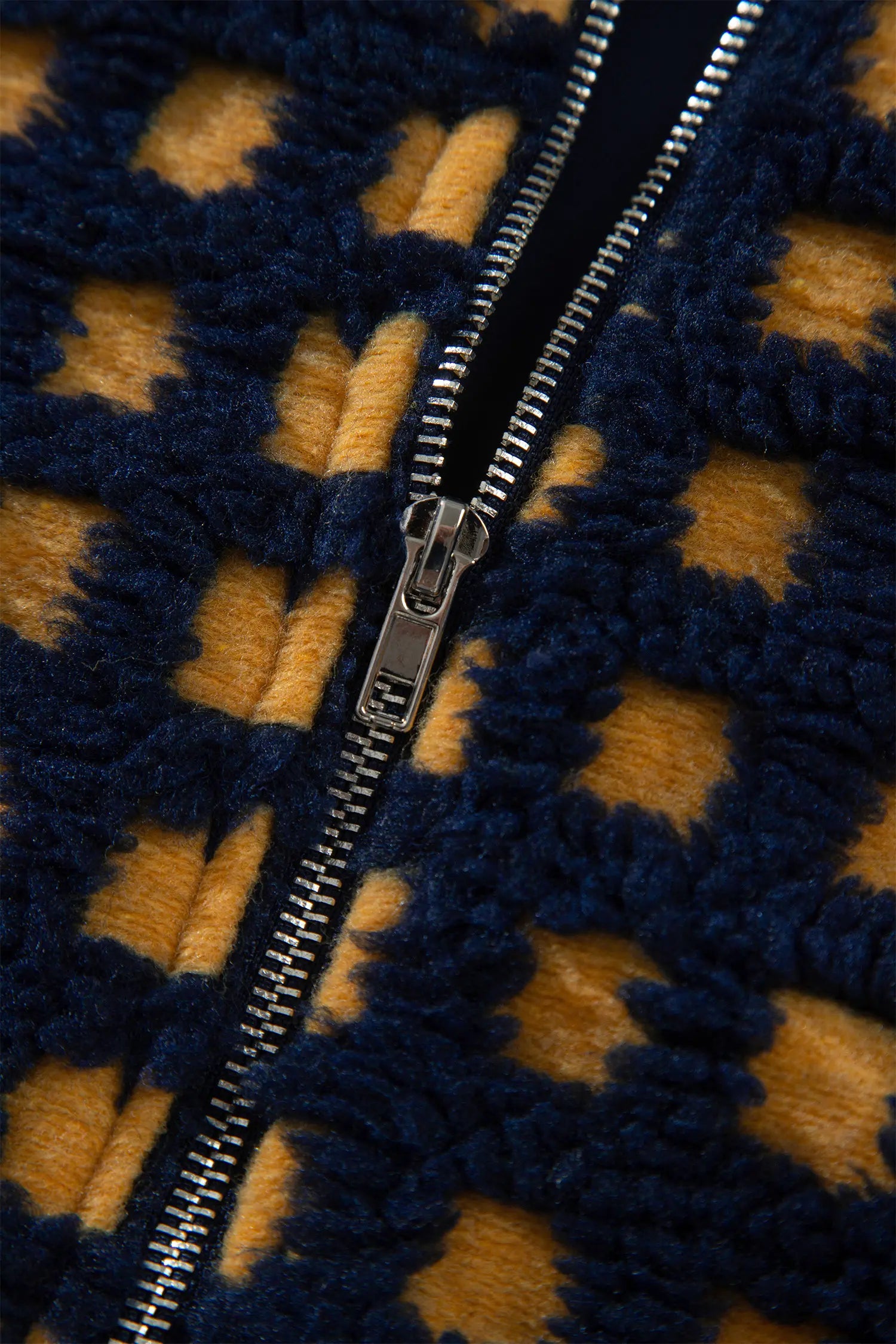 Close-up of metal zipper on navy and mustard check sherpa fleece