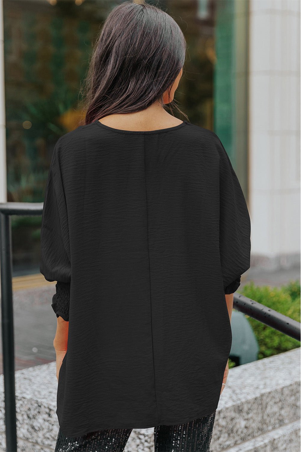 Person wearing a black oversized shirt standing outdoors.