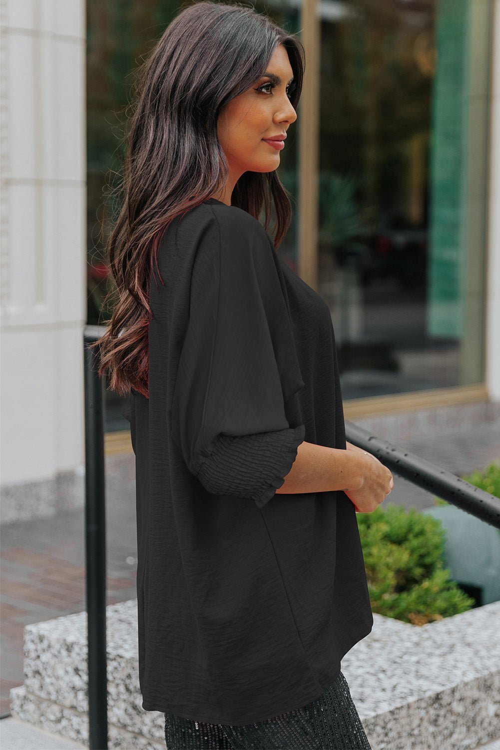 Woman wearing a black outfit standing outdoors with blurred background