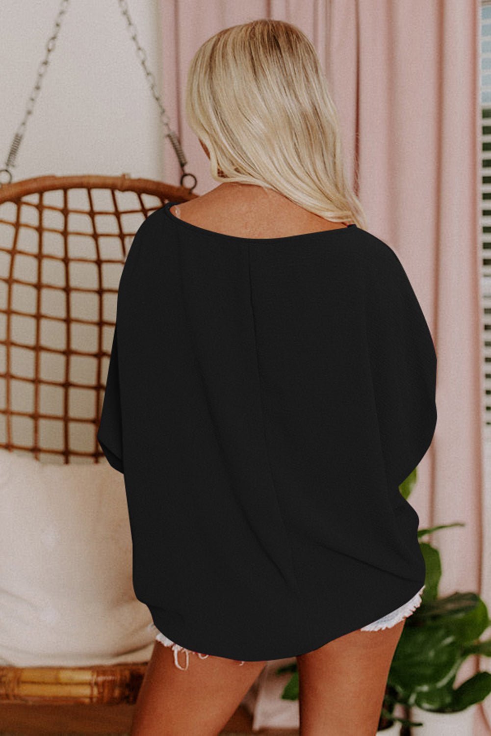 Person wearing a black oversized top and white shorts in a casual setting.