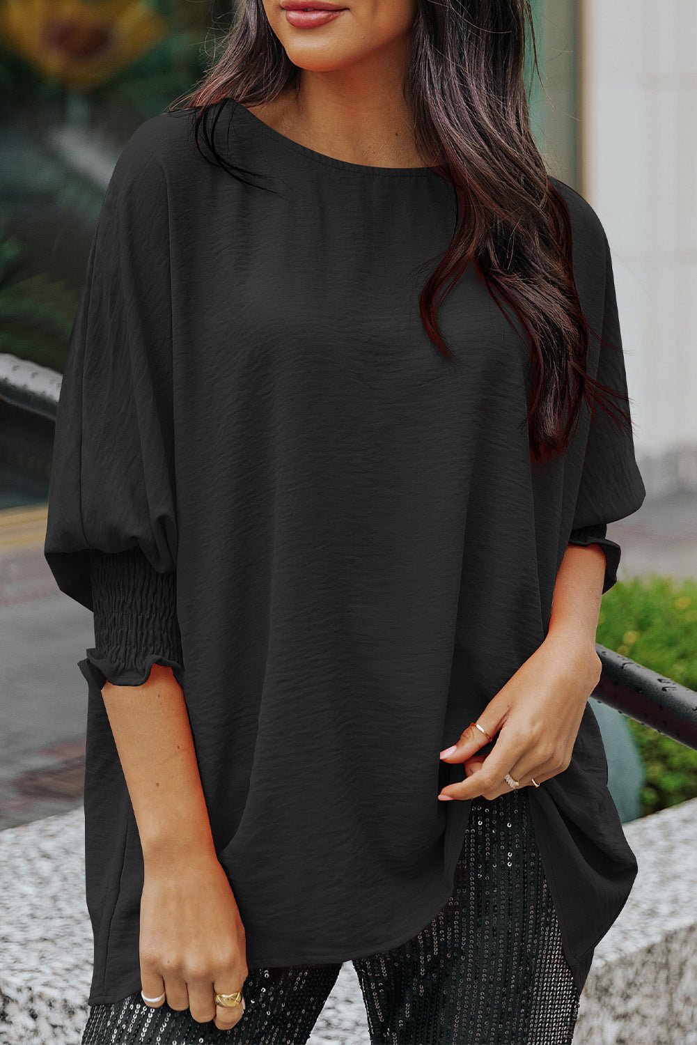 Woman wearing a black oversized top with a blurred background