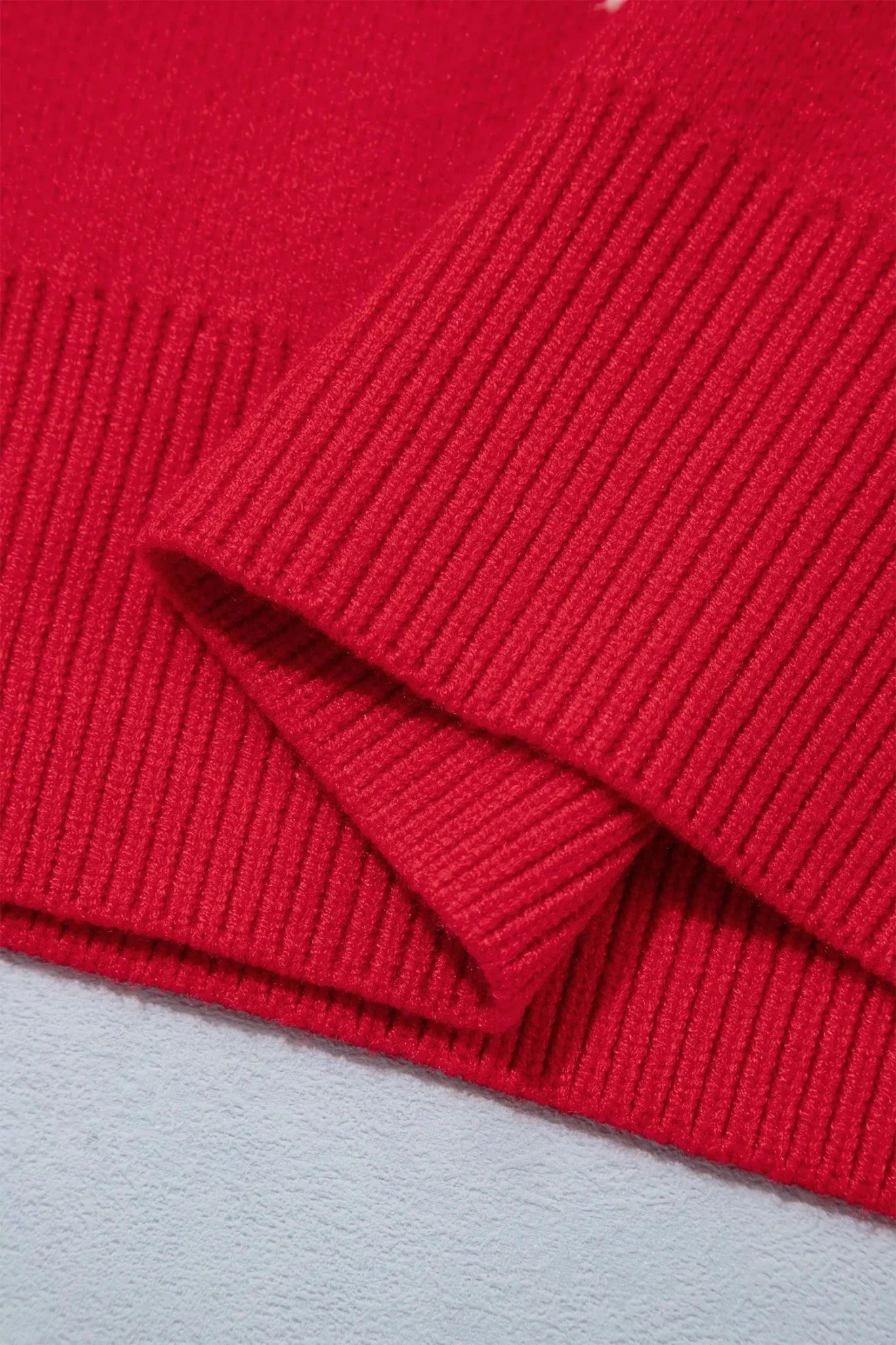 Close-up of bright red ribbed knit cuff with small white graphic detail.
