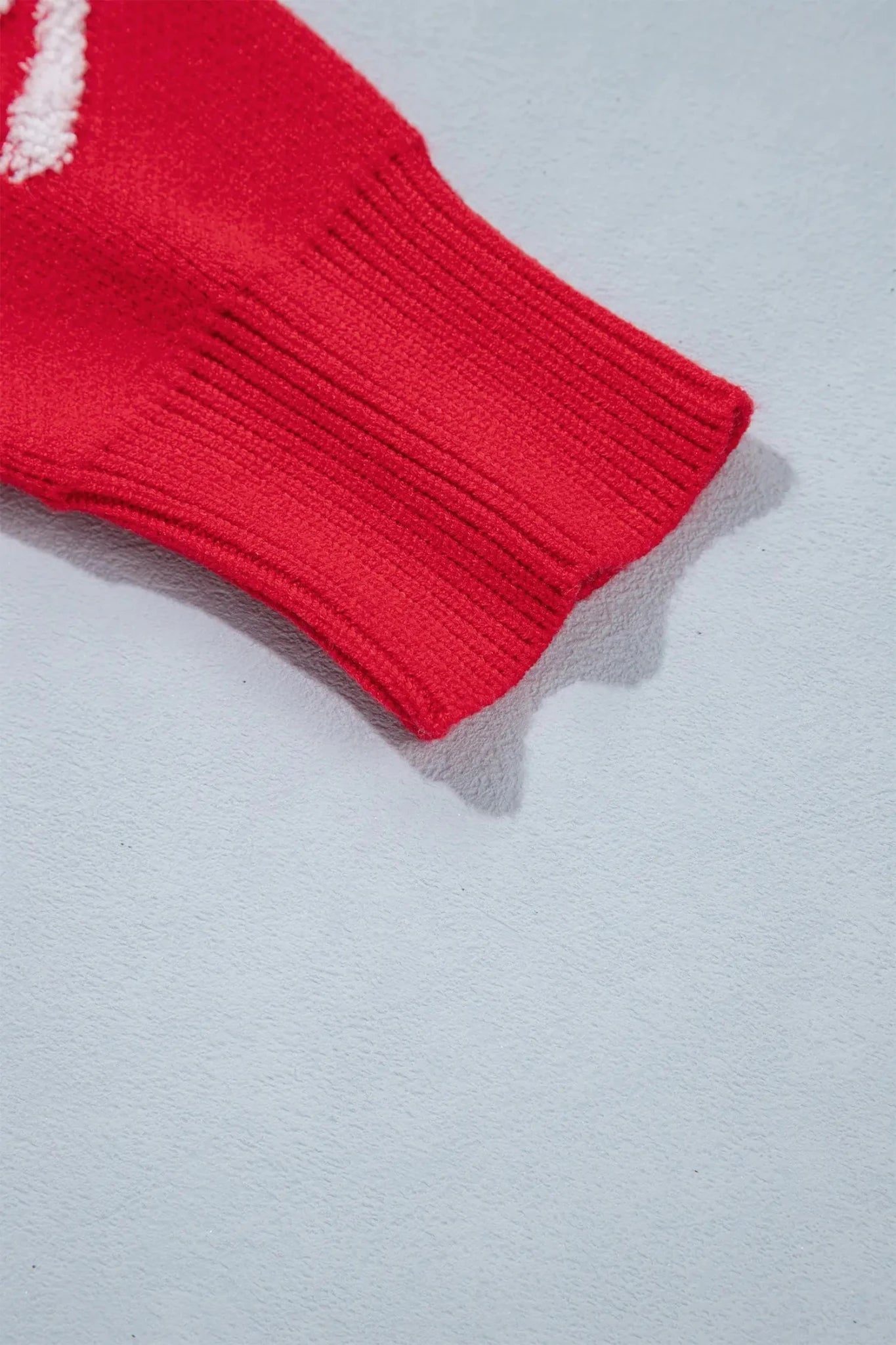 Close-up of red knit sweater with textured white knitted bow motifs.