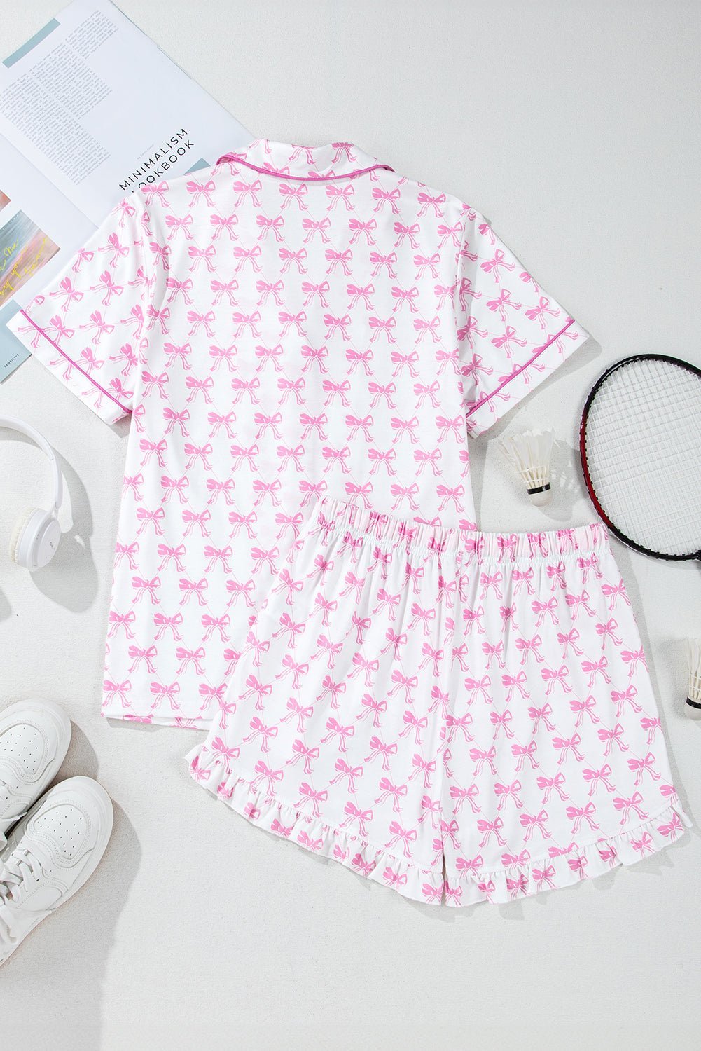 Pink and white pajama set with bow pattern on a light gray surface.