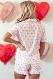 Woman wearing a pink bow-patterned pajama set with heart-shaped balloons in the background.