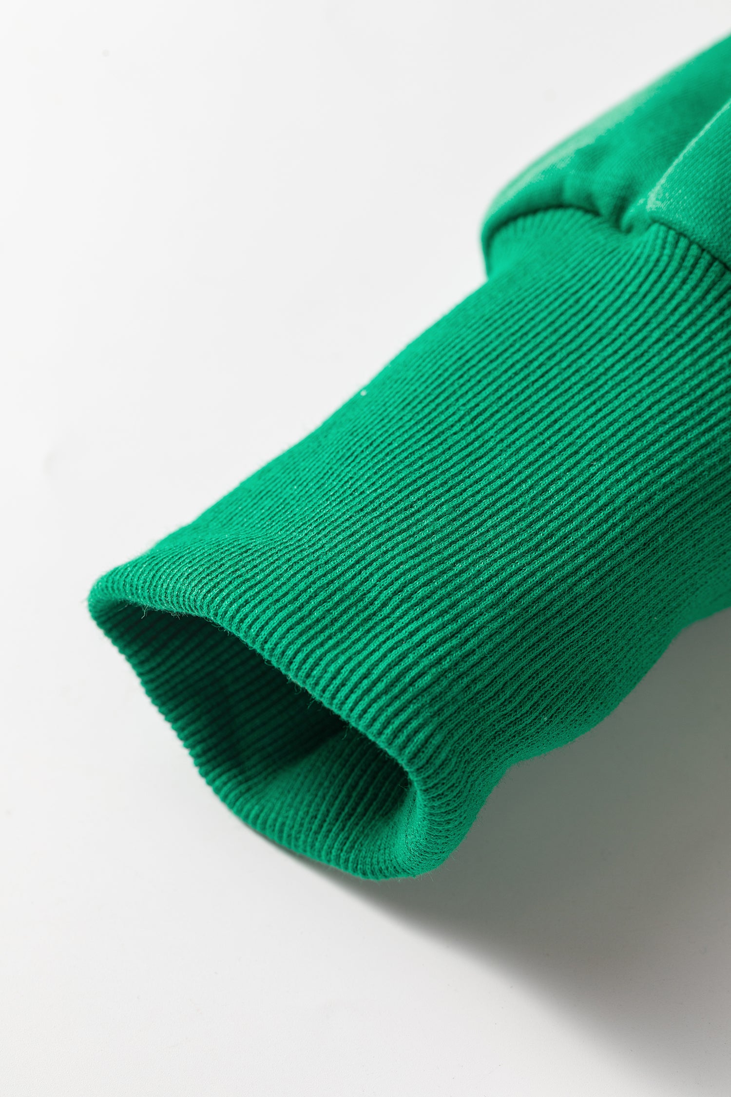 Close-up of ribbed sleeve cuff on bright green cropped hoodie