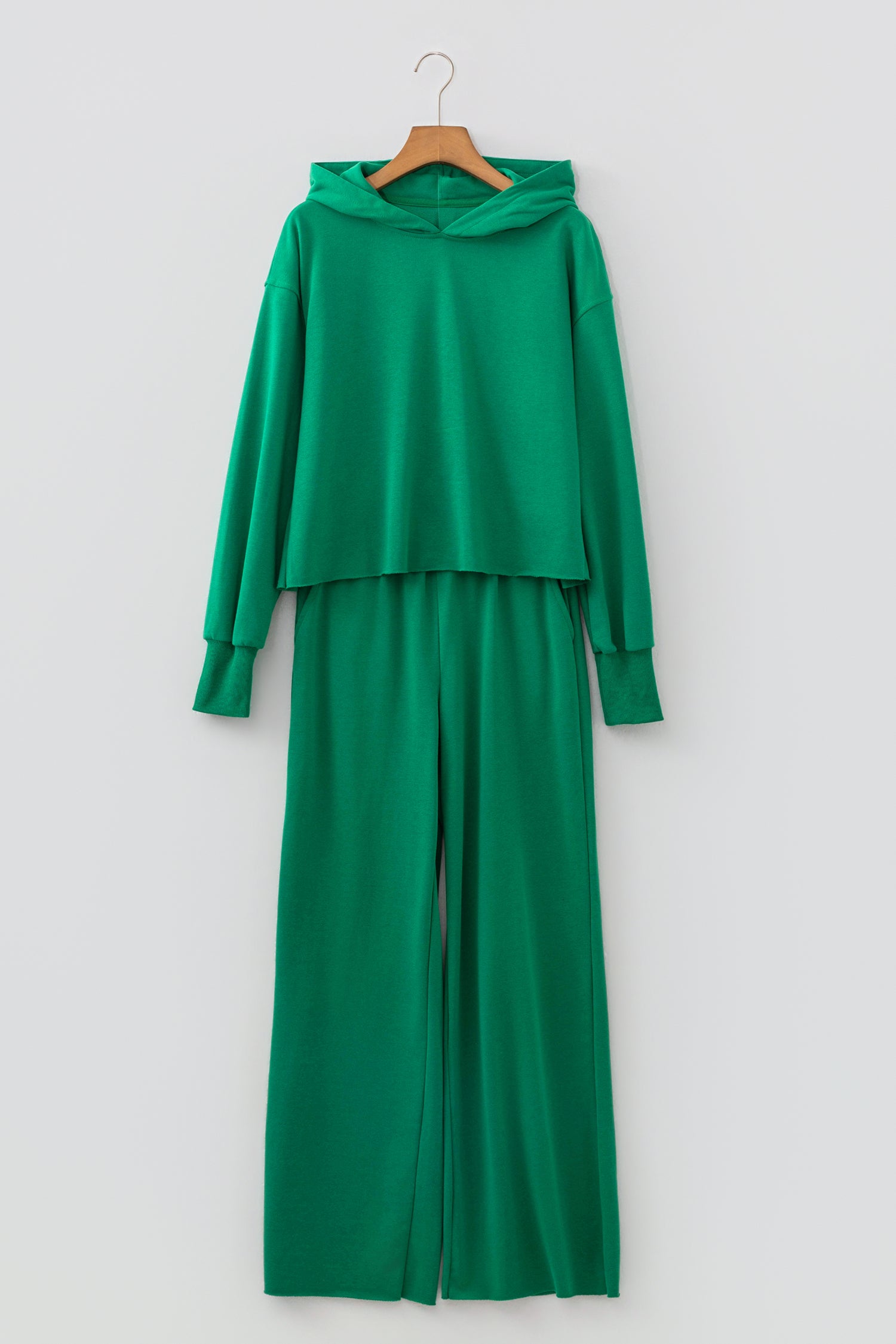 Bright green cropped hoodie and wide leg pants set on a hanger, front view